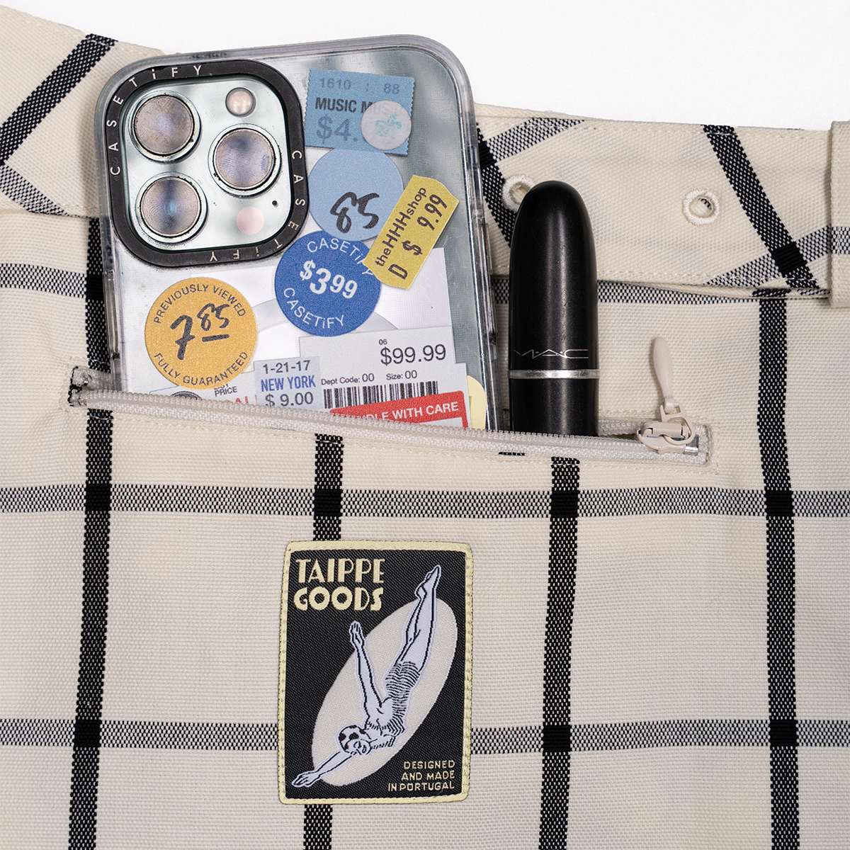 Open bag with phone, pen, and Taippe Goods label on plaid fabric background