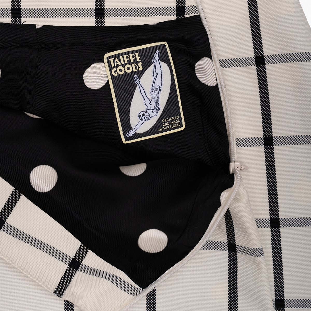 Black garment with a patch labelled 'Taippe Goods' on a checkered skirt