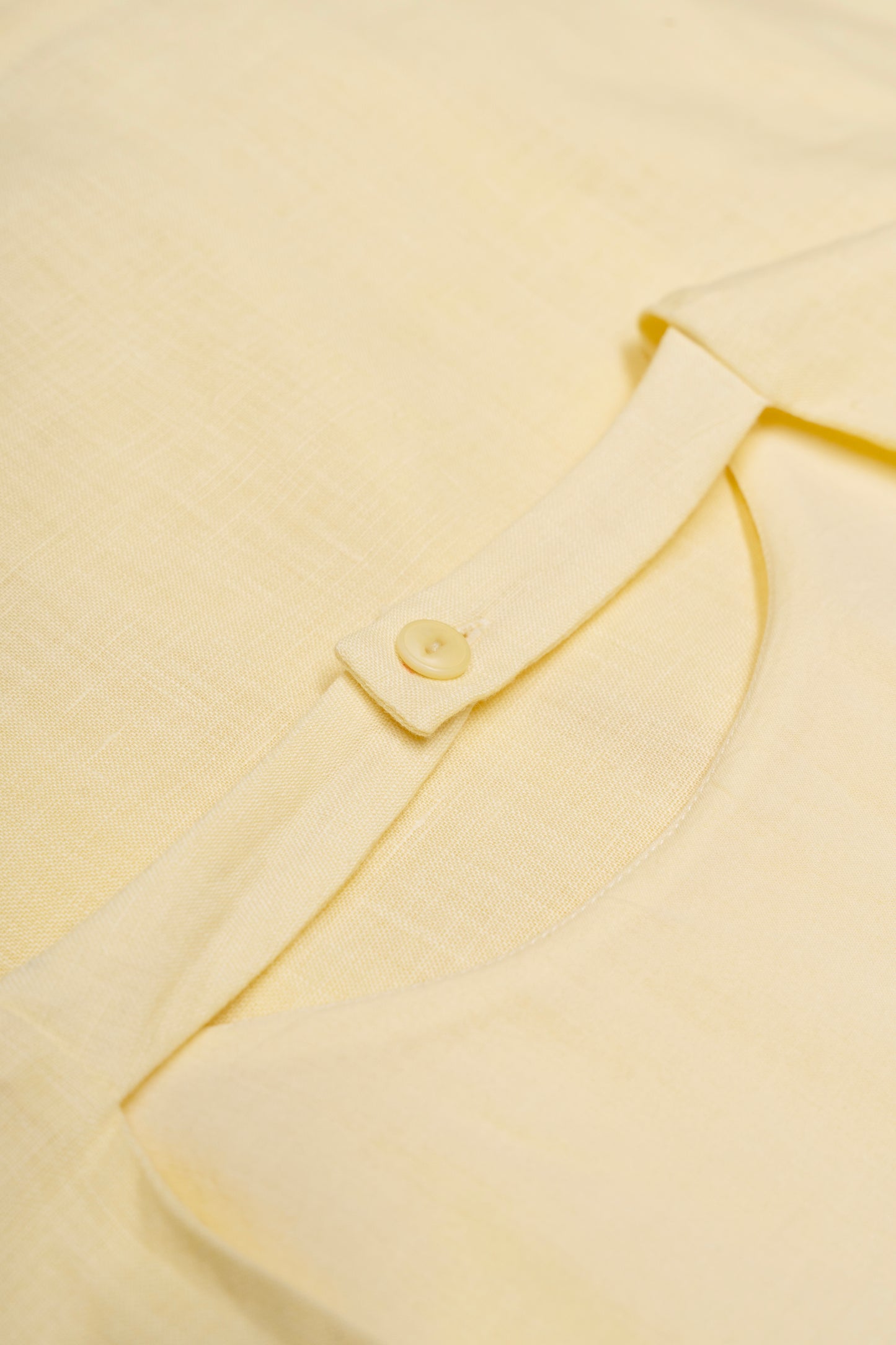 Close-up of a light yellow dress with a button detail