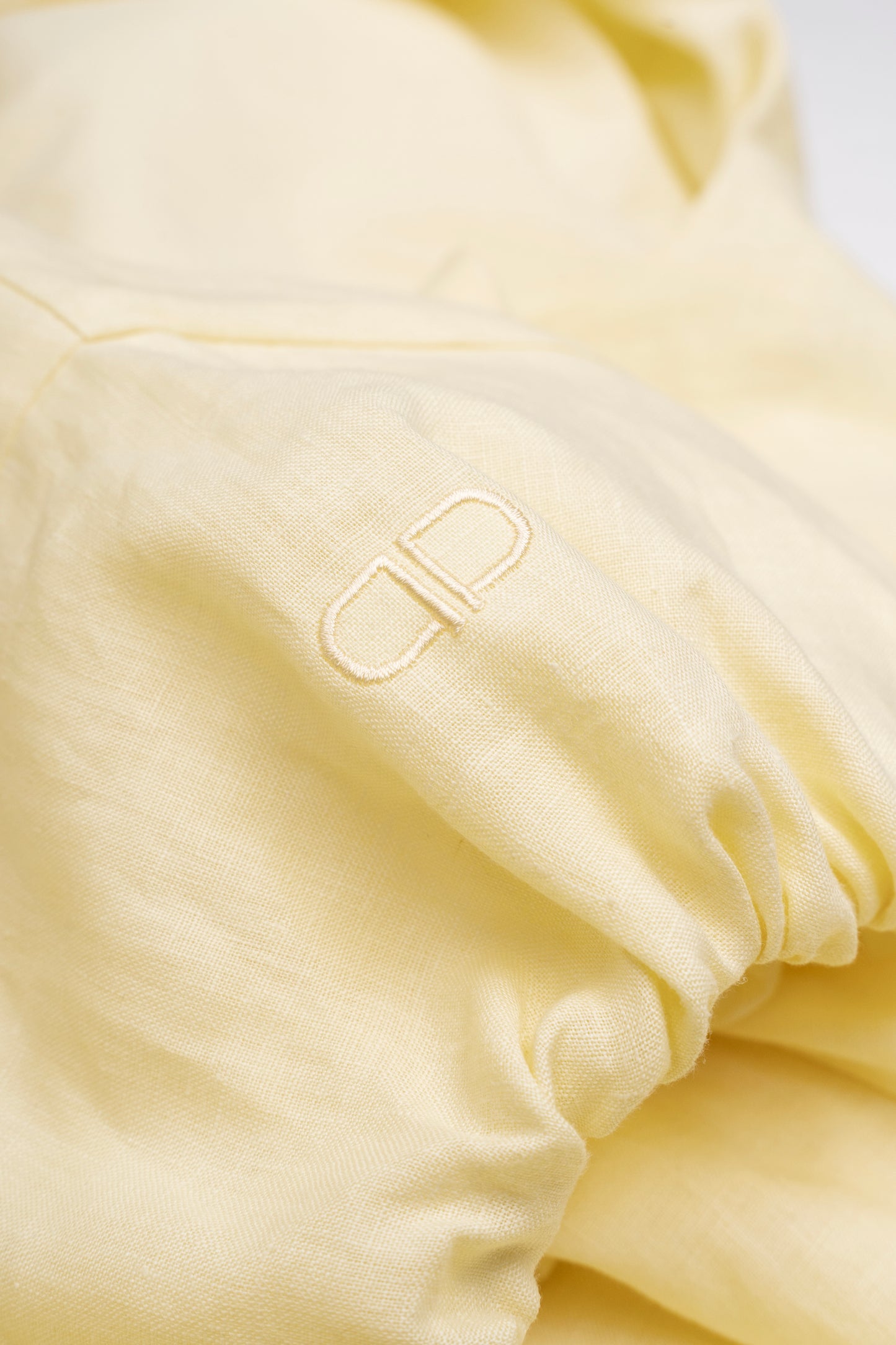 Close-up of a light yellow fabric with a logo, on a white background
