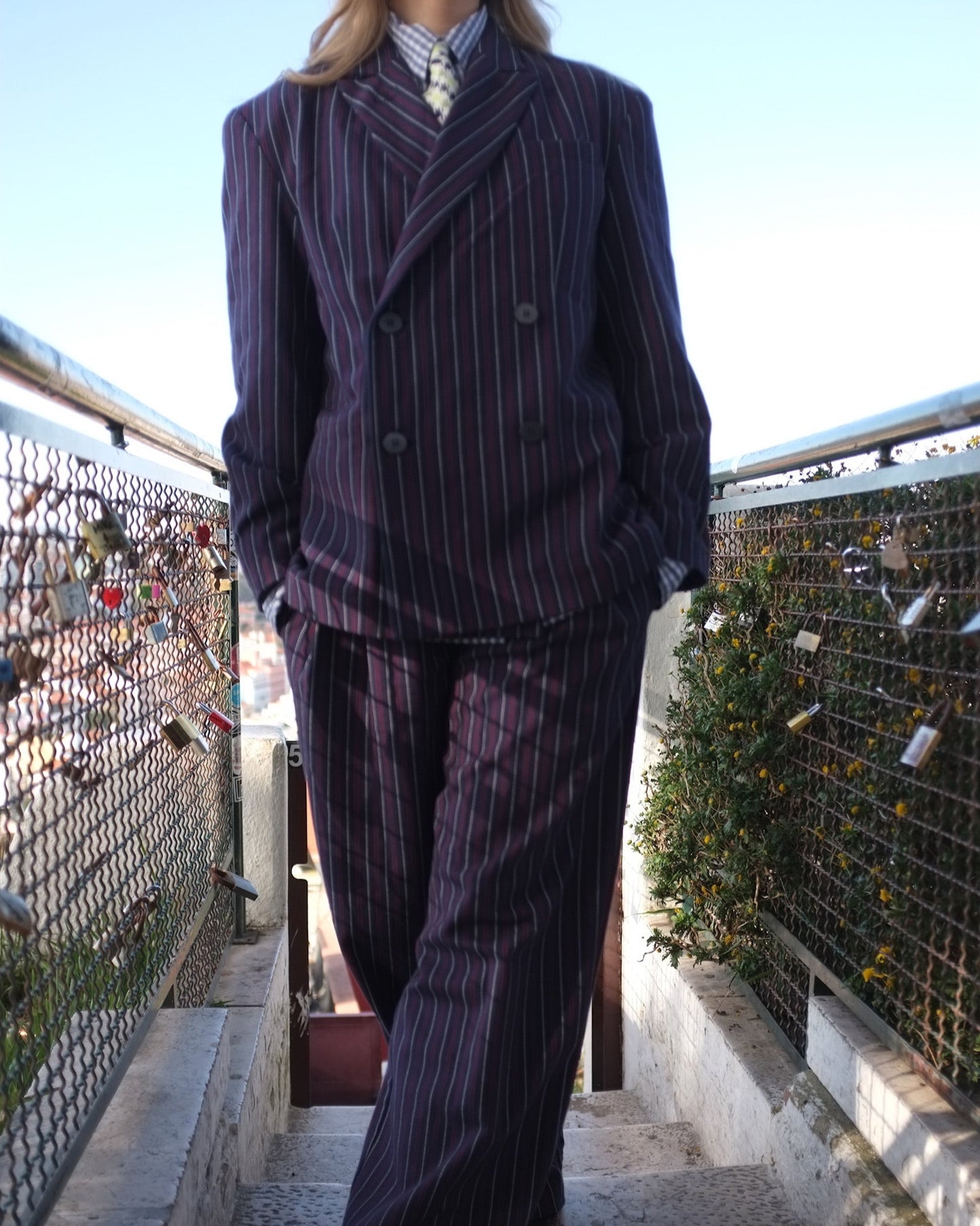 Person wearing a pinstripe suit standing on a bridge with a scenic background