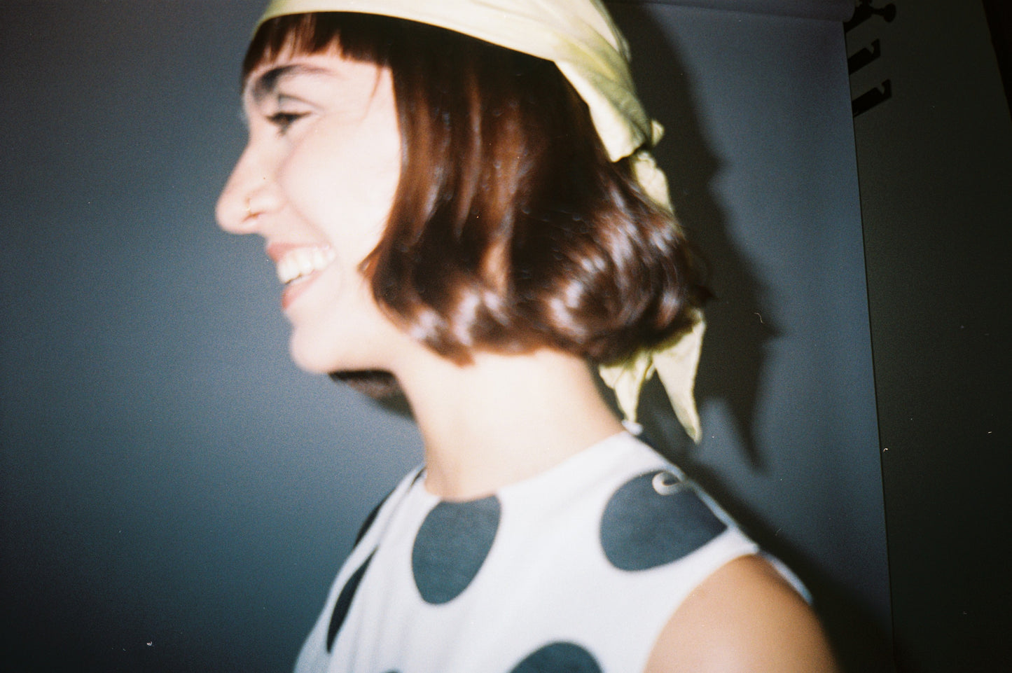 Woman wearing a polka dot dress and headscarf against a dark background