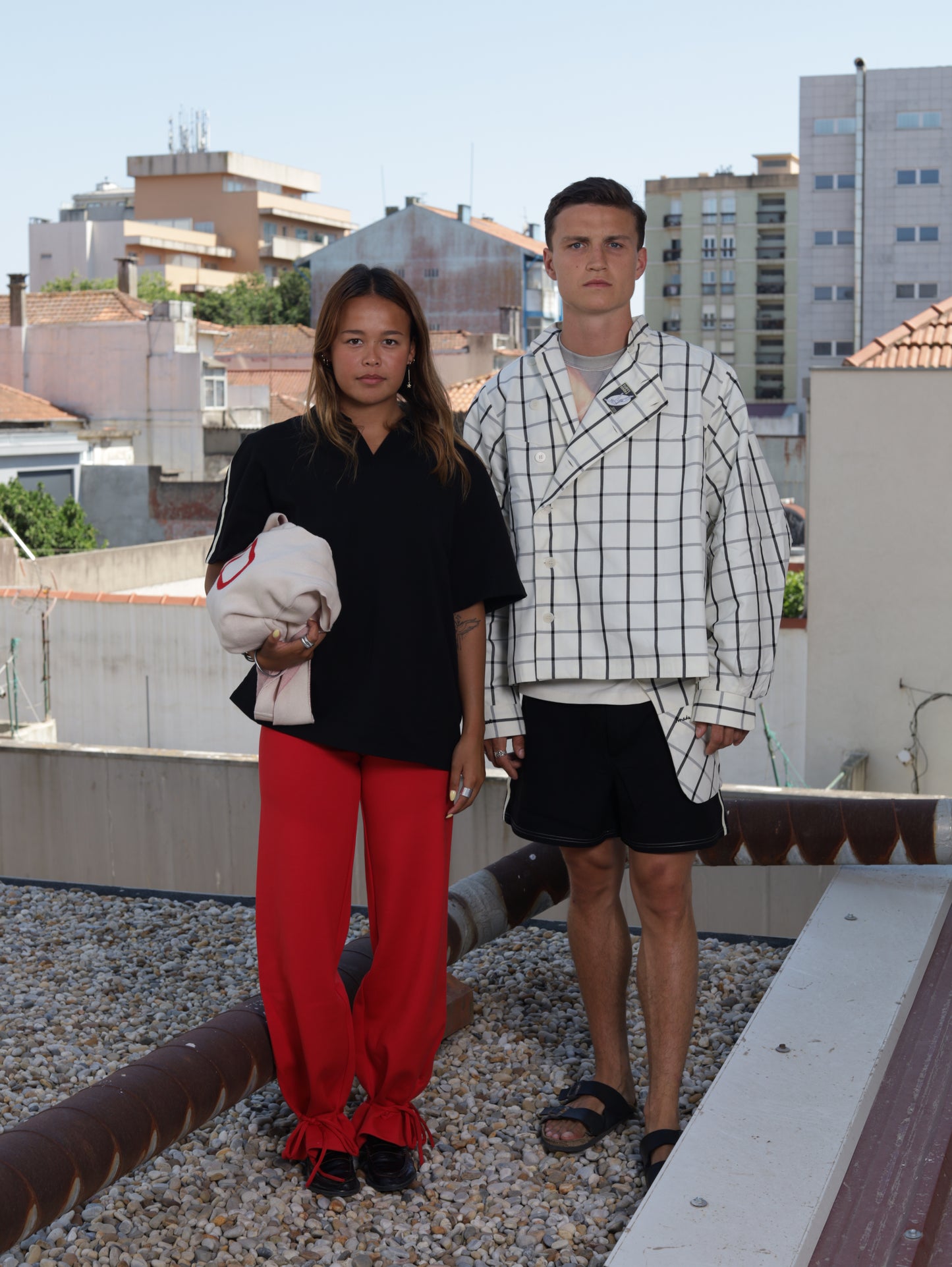 Two people standing on a rooftop with buildings in the background