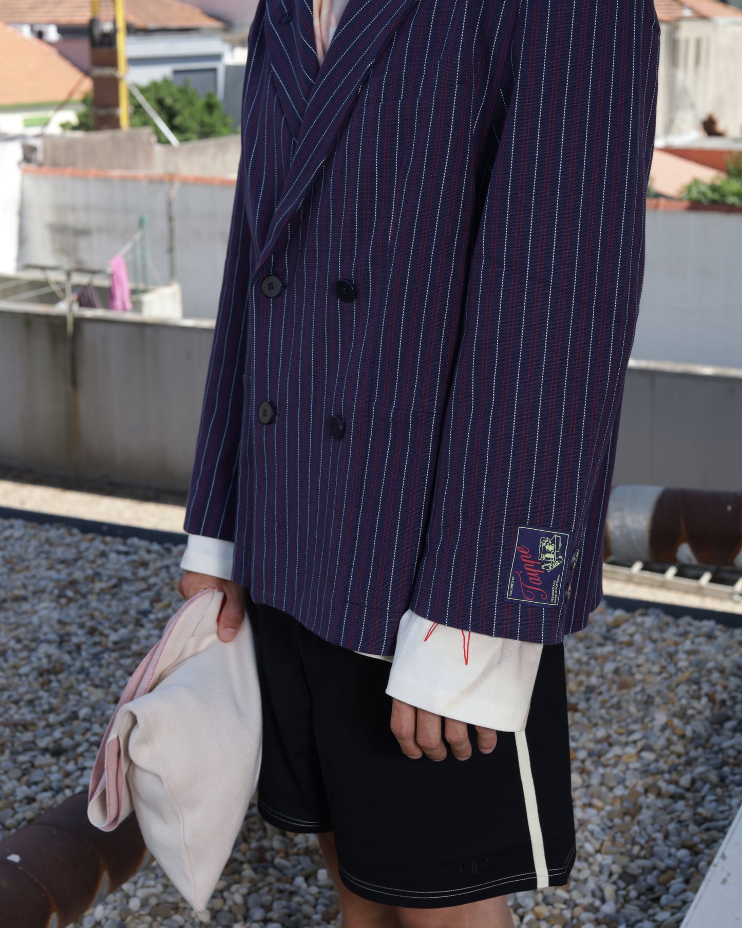 Person wearing a striped suit jacket with a brand logo outdoors.