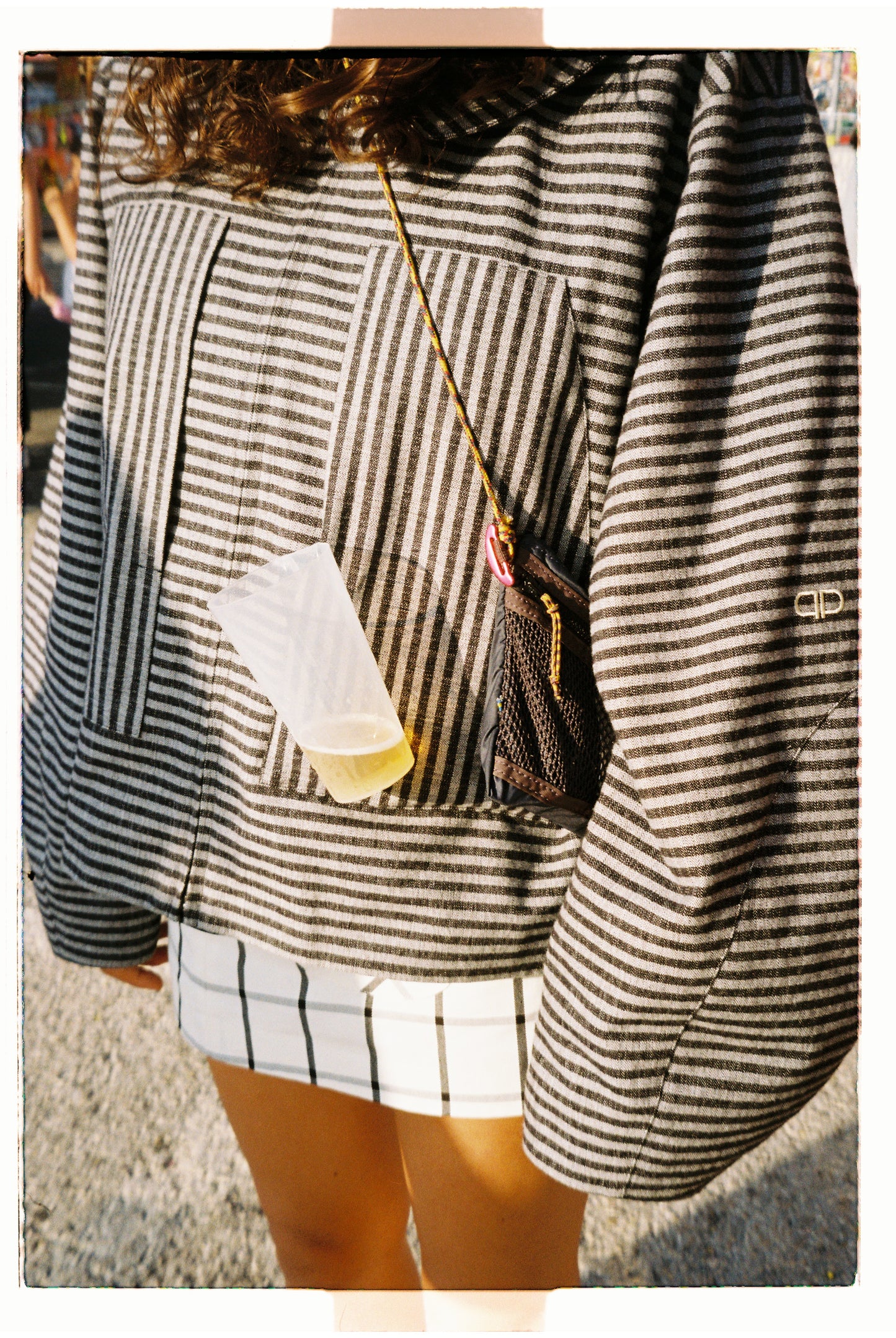 Person wearing a striped jacket with a small bag over their shoulder, standing outdoors.