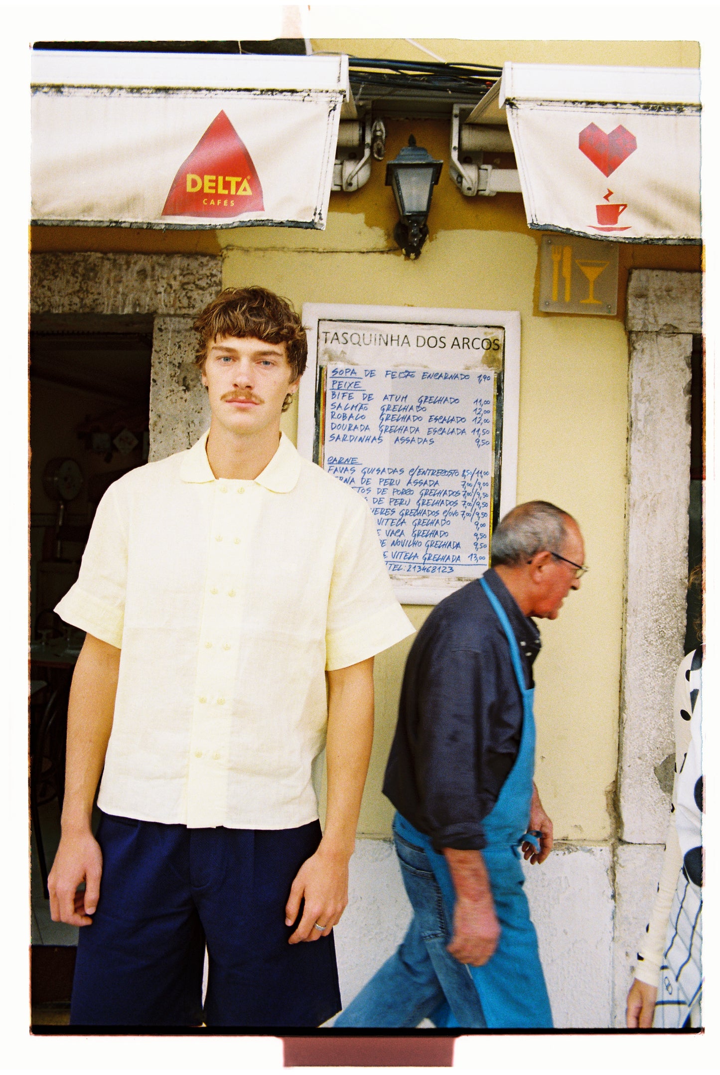 Man in a butter yellow shirt and navy shorts.