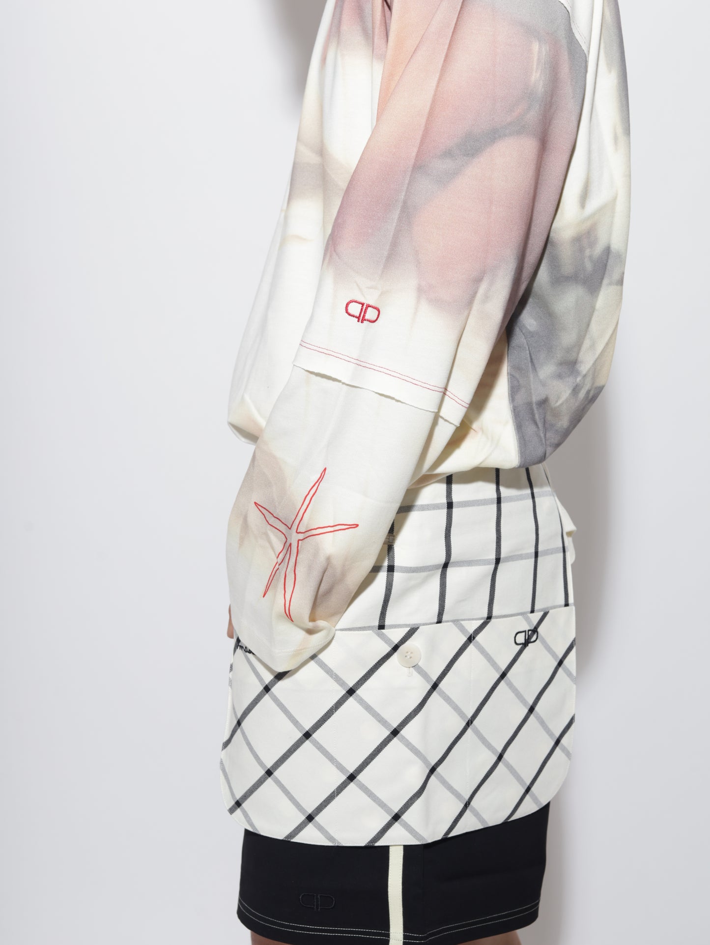 Close-up of a person wearing a plaid belt bag with a white shirt underneath on a light gray background