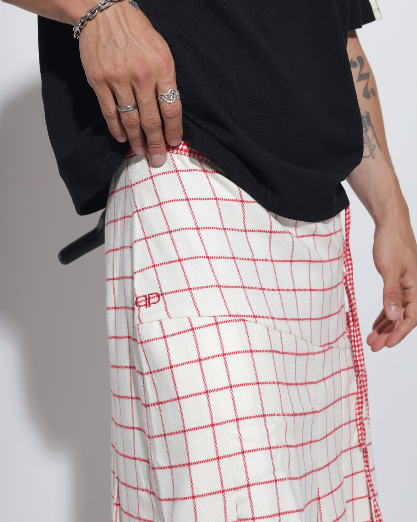 Person wearing a skirt with red grid pattern on a plain background