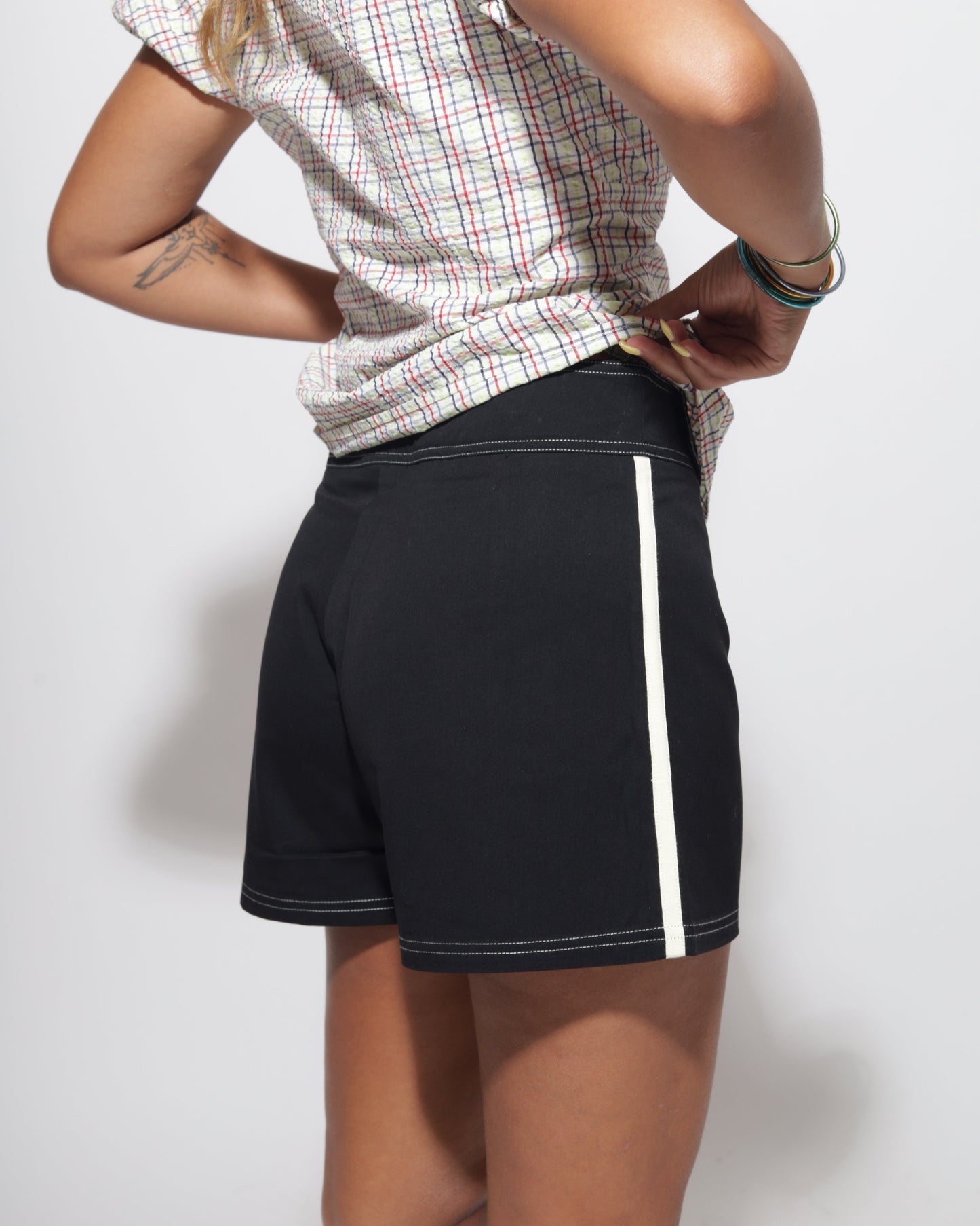 Person wearing black shorts with yellow trim on a plain background