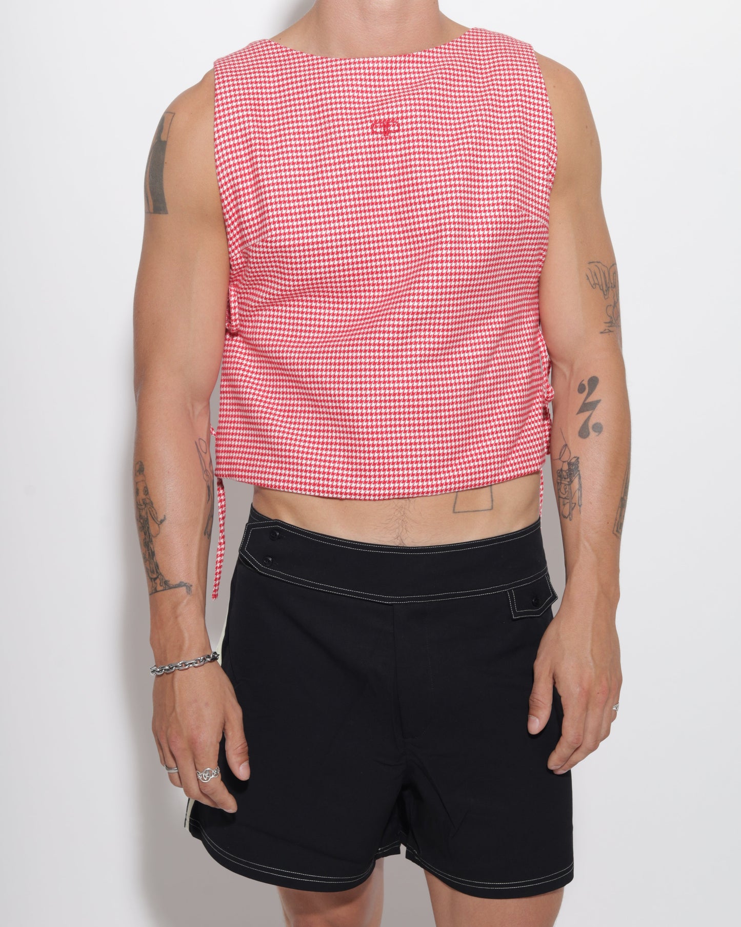 Person wearing a red checkered vest and black shorts on a white background