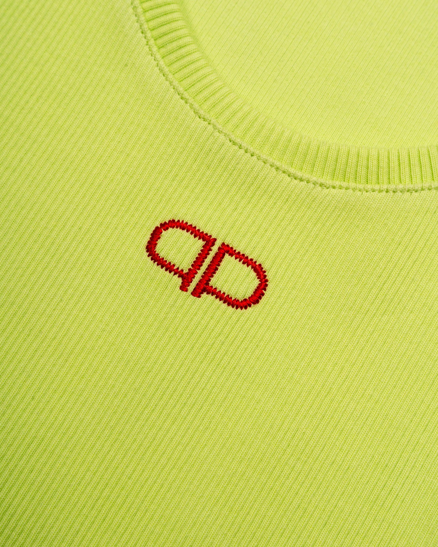 Close-up of a lime tank top with a red logo on a matching background