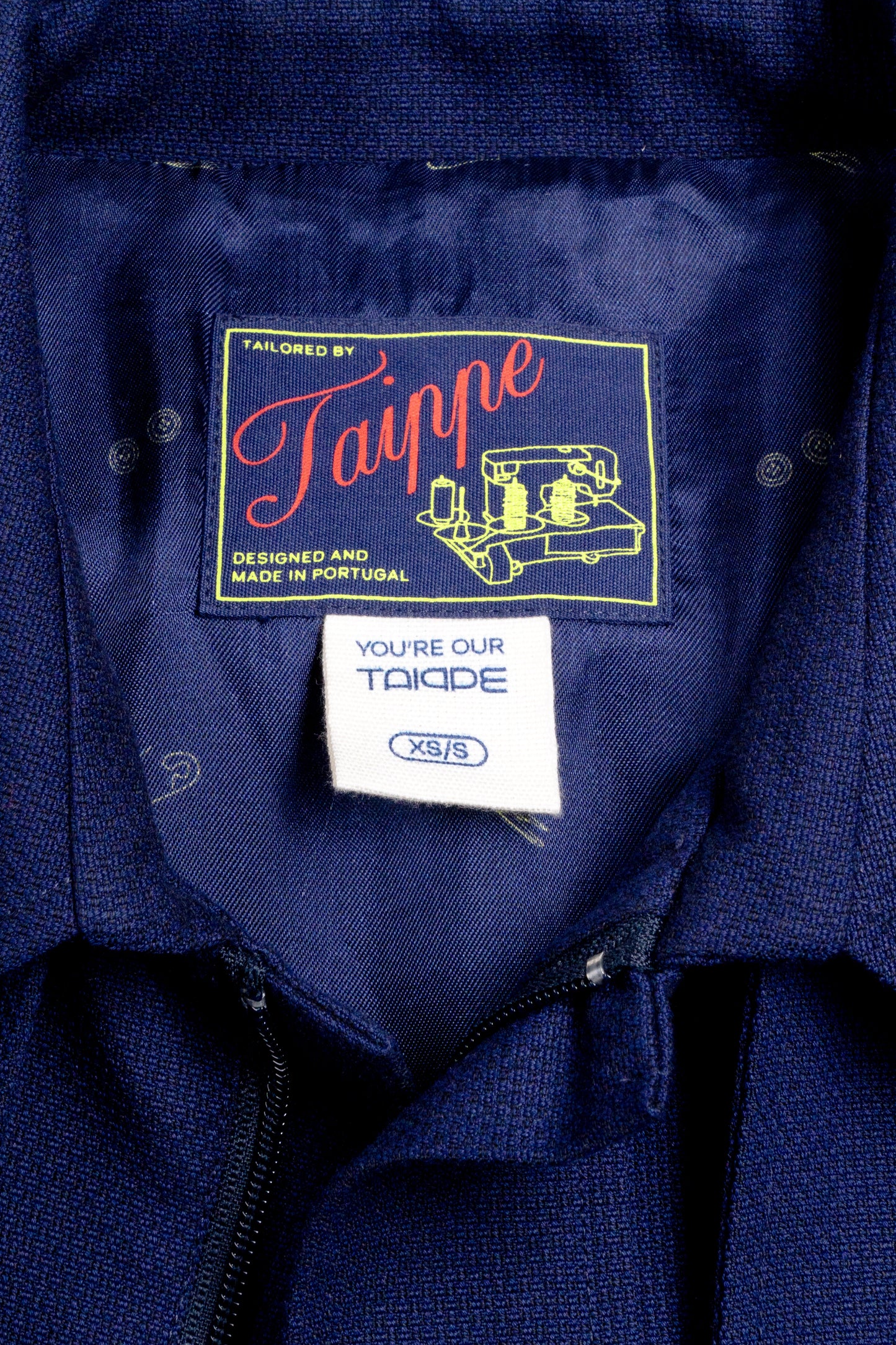 Close-up of a navy blue coat with 'Taippe' branding on a label.