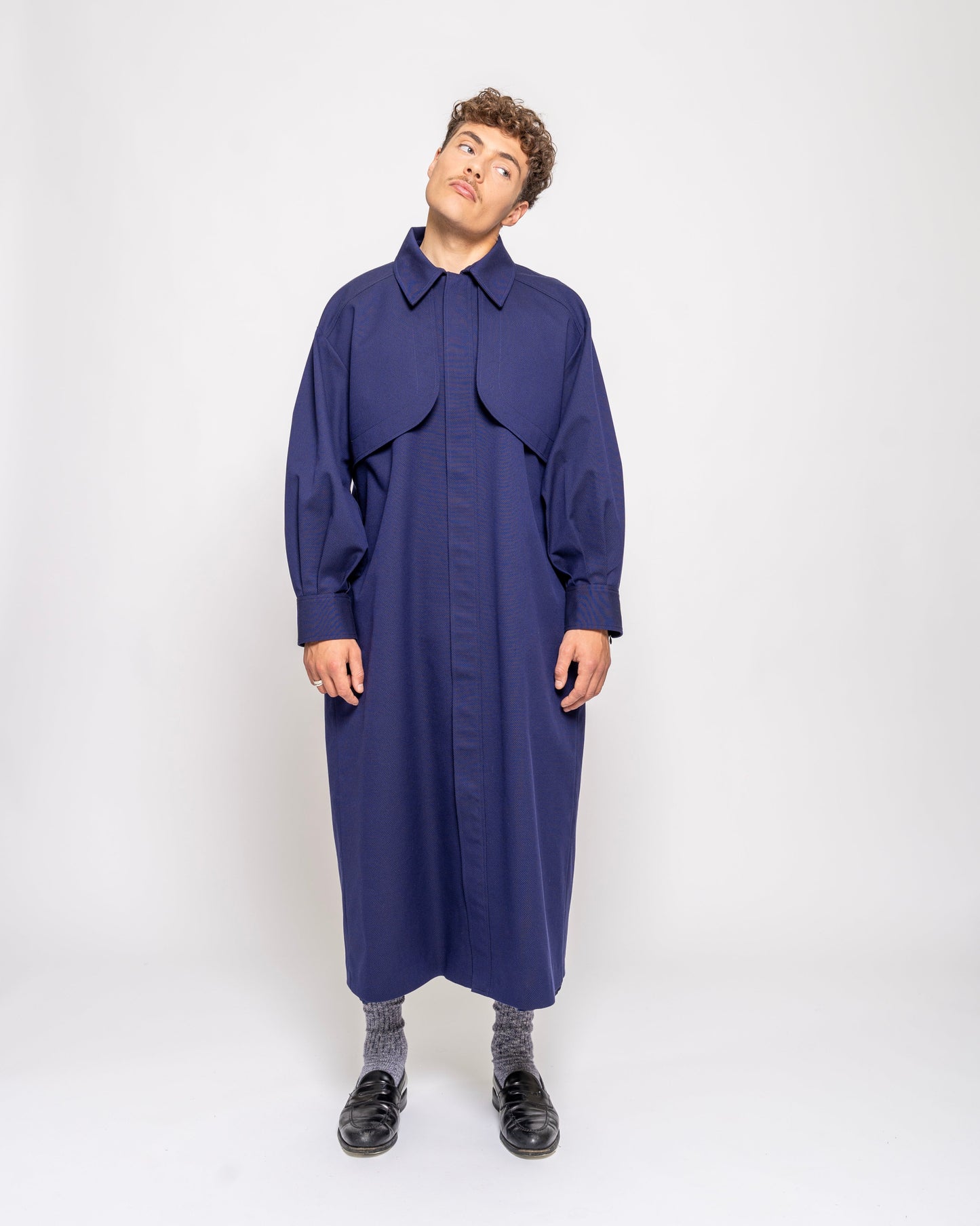 Person wearing a long blue coat on a white background