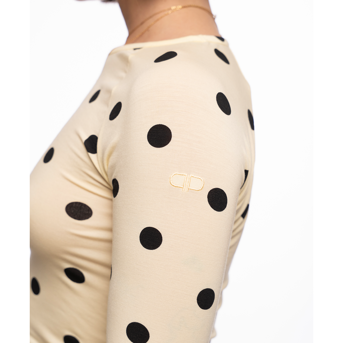 Yellow long-sleeve top with black polka dots on a white background