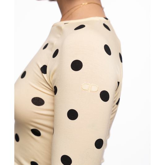 Yellow long-sleeve top with black polka dots on a white background