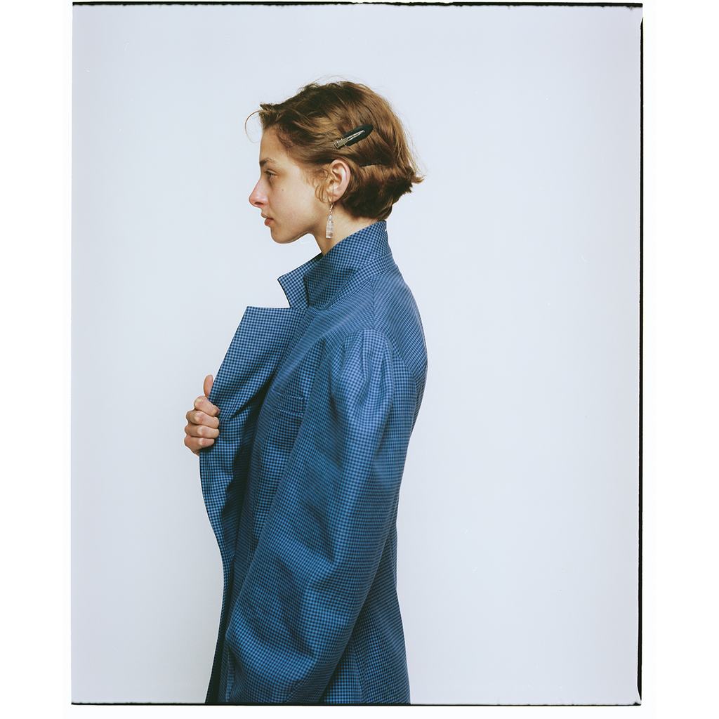 Person wearing a blue checkered blazer against a white background