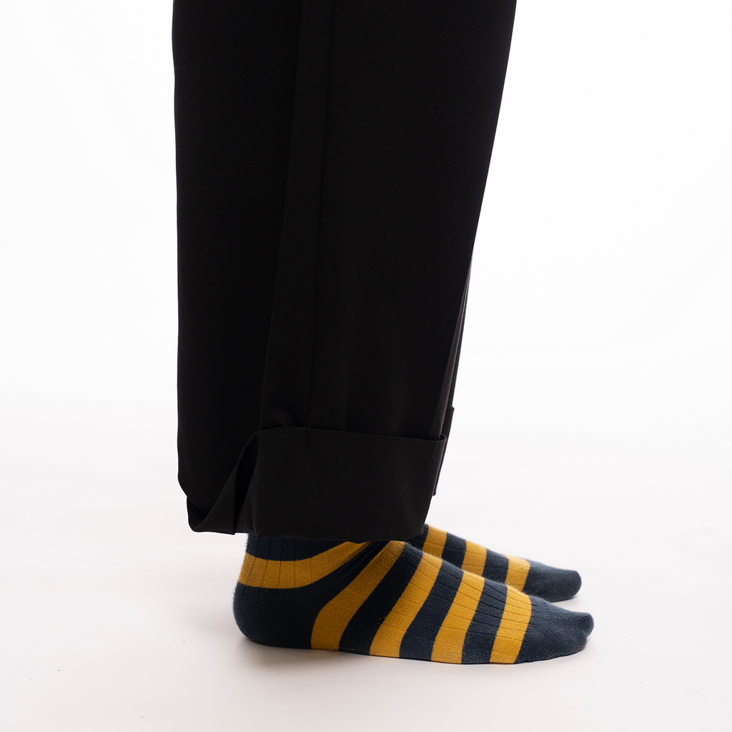 Black pants with striped yellow and blue socks on a white background