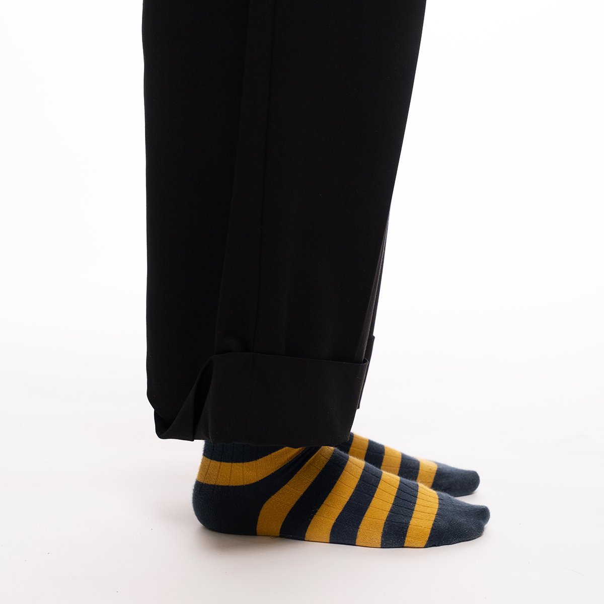 Black pants with striped yellow and blue socks on a white background