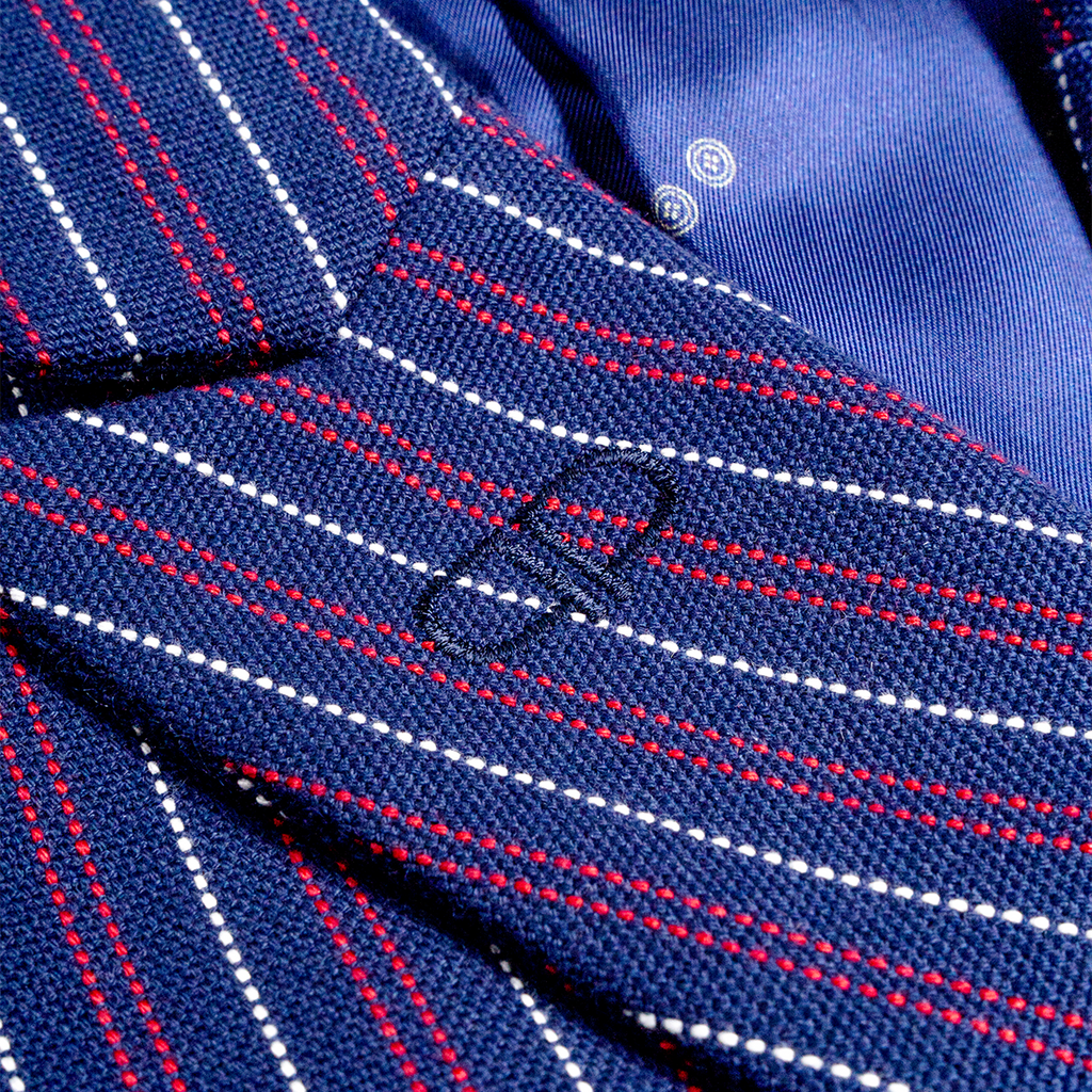 Close-up of a blue striped  blazer with red and white lines and a brand logo.