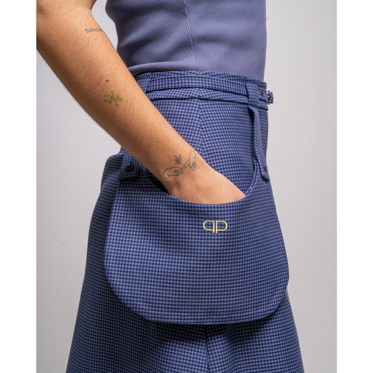 Person wearing a blue checkered skirt with external pockets with a logo 