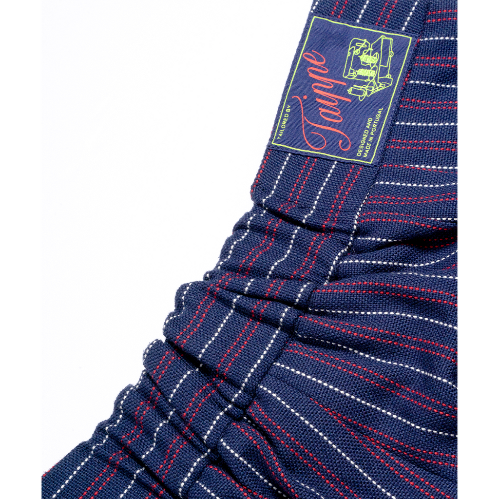 Close-up of blue pinstripe pants with a brand label on a white background