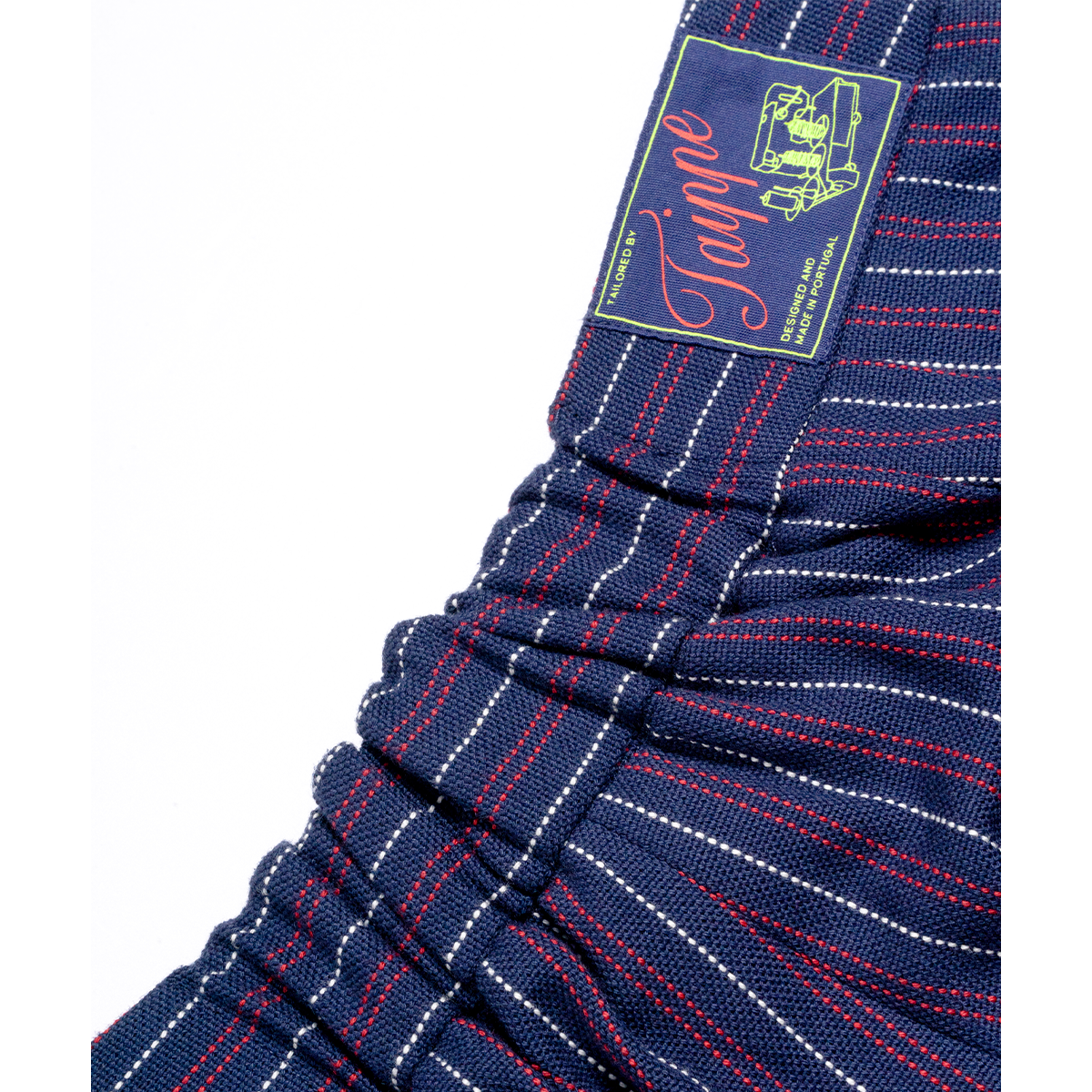 Close-up of blue pinstripe pants with a brand label on a white background