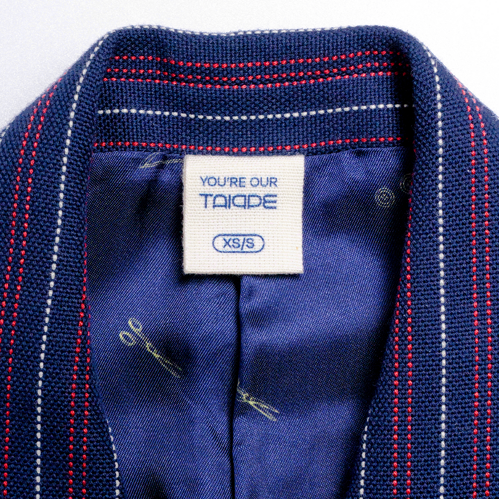 Close-up of a blue garment with a visible tag, showing brand and size information.