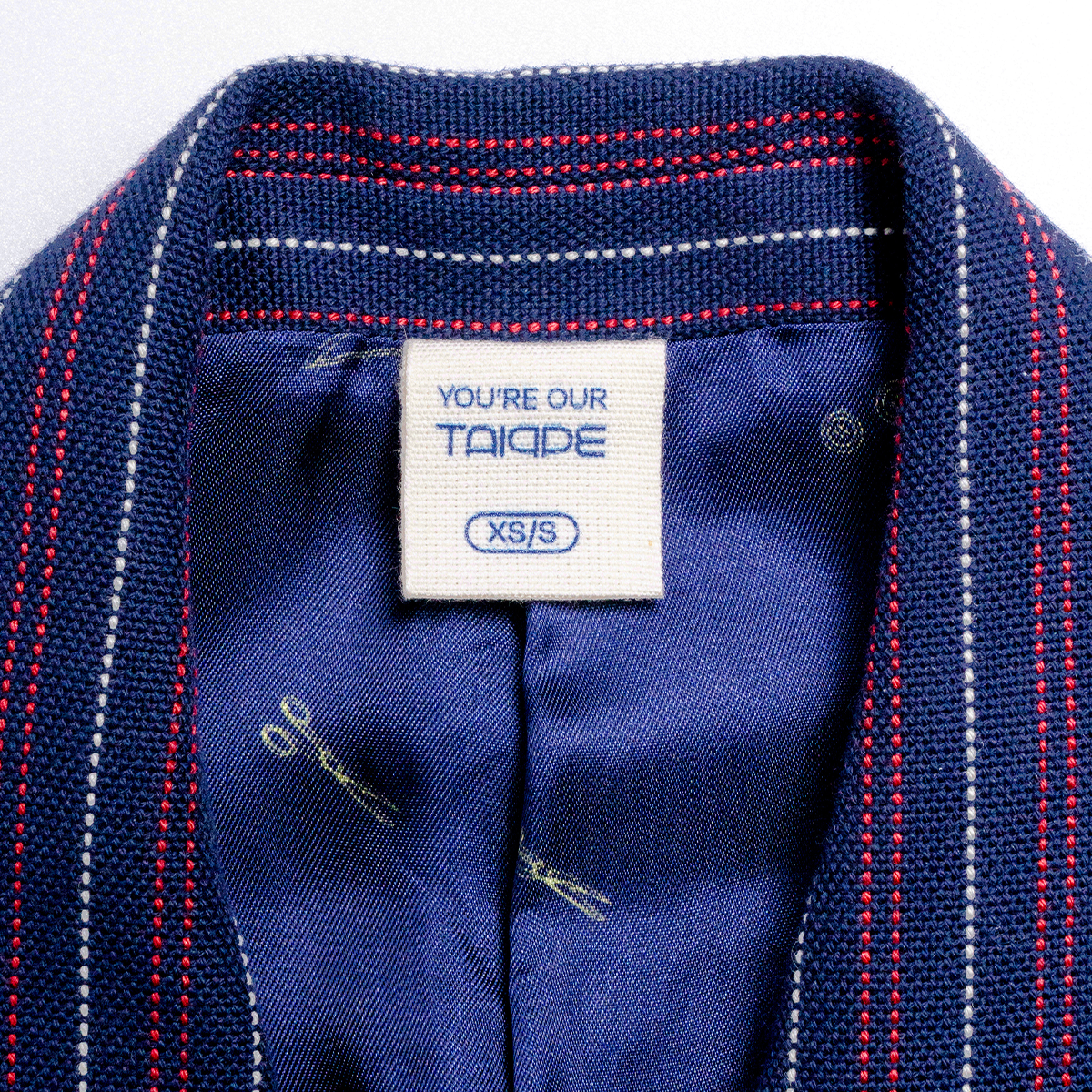 Close-up of a blue garment with a visible tag, showing brand and size information.