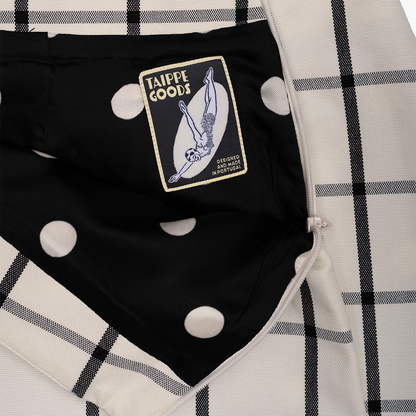 Black garment with a patch labelled 'Taippe Goods' on a checkered skirt