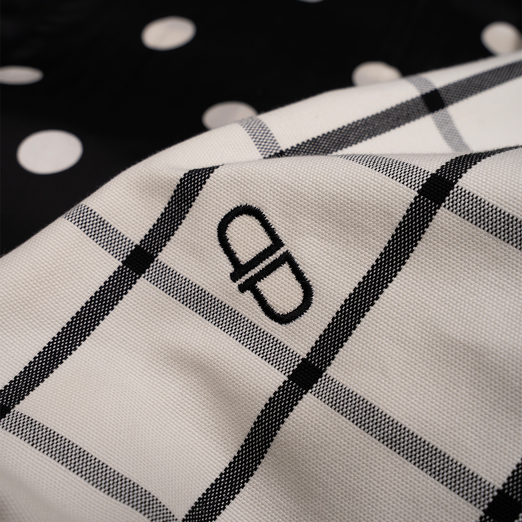 Close-up of a white and black checkered pattern with a brand logo on a dark background.