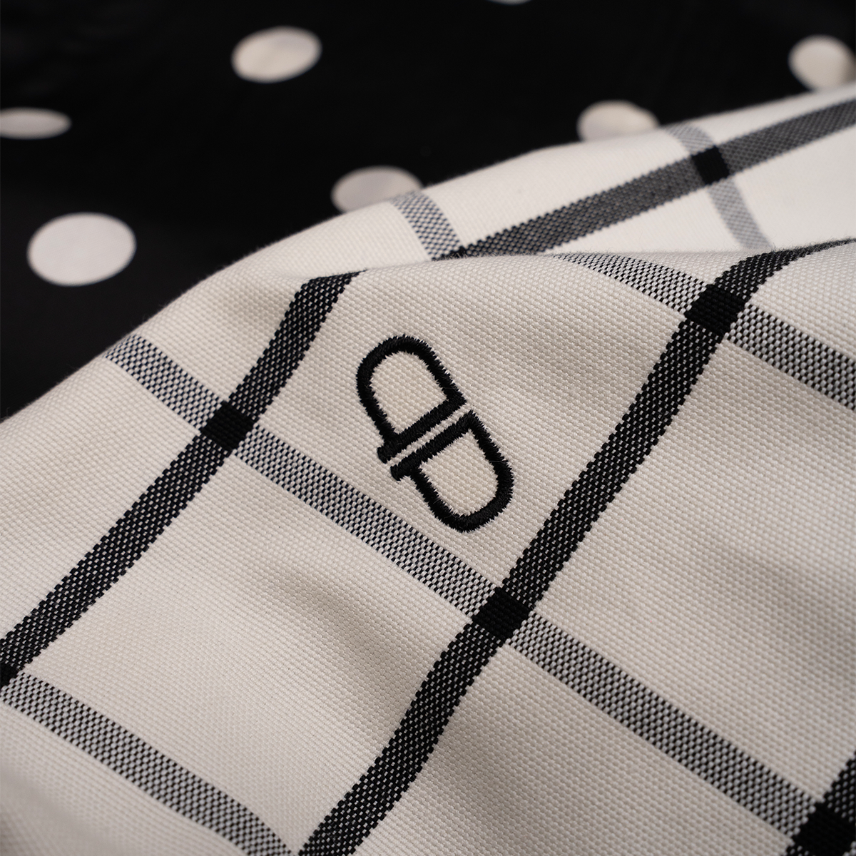 Close-up of a white and black checkered pattern with a brand logo on a dark background.