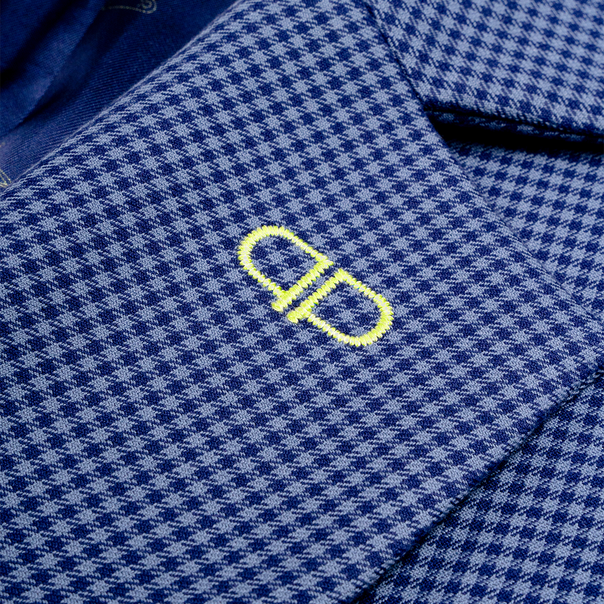 Close-up of a blue checkered blazer with a yellow logo 