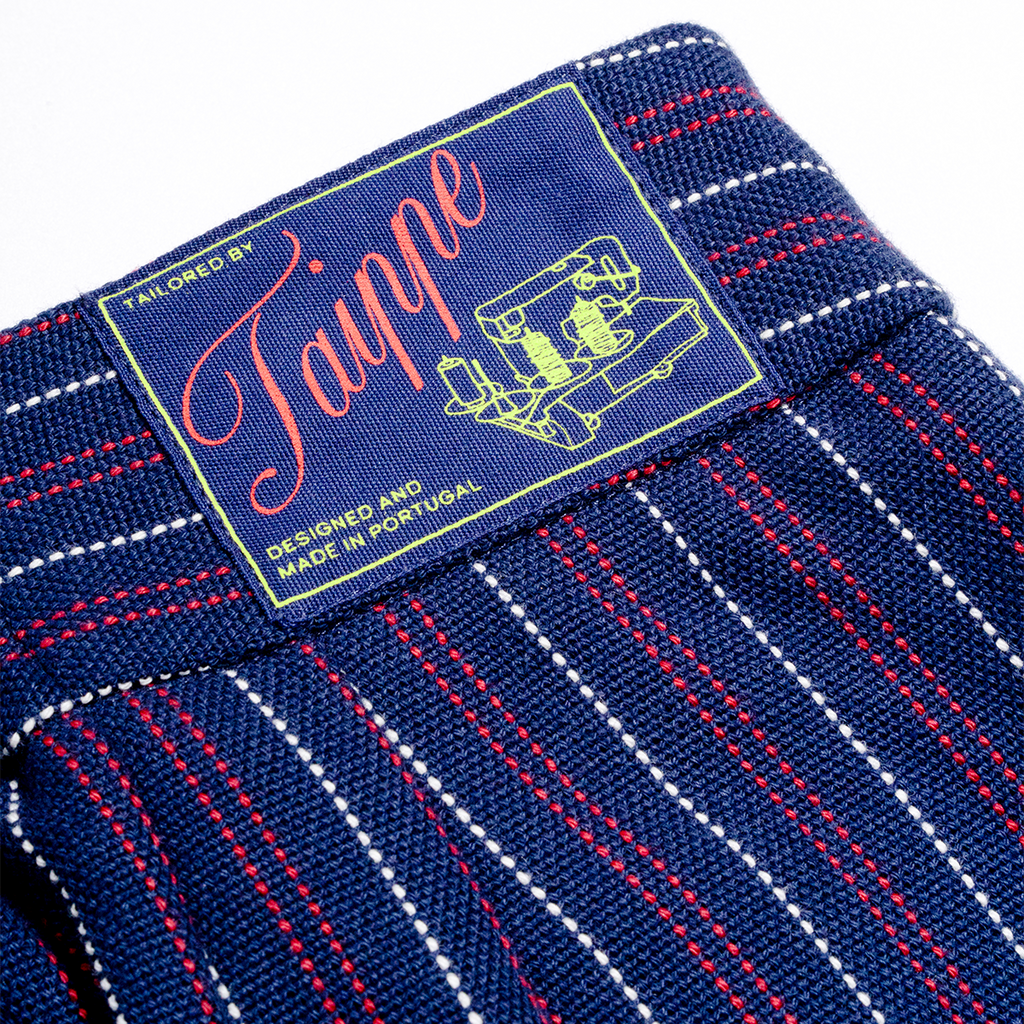 Close-up of a blue fabric with red and white stitching and a 'Taippe' label.