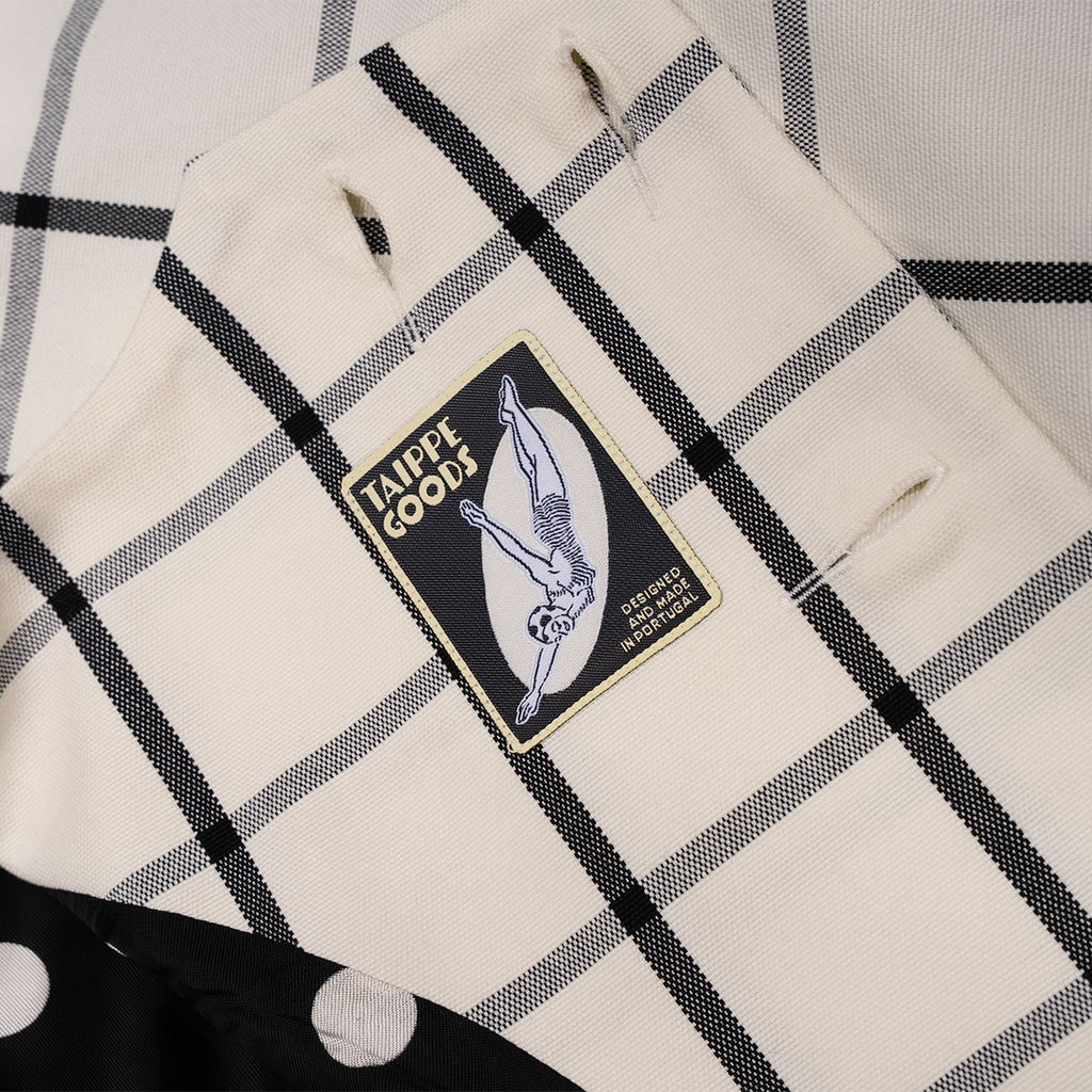 Checkered fabric with a patch labeled 'Taippe Goods' on a white background