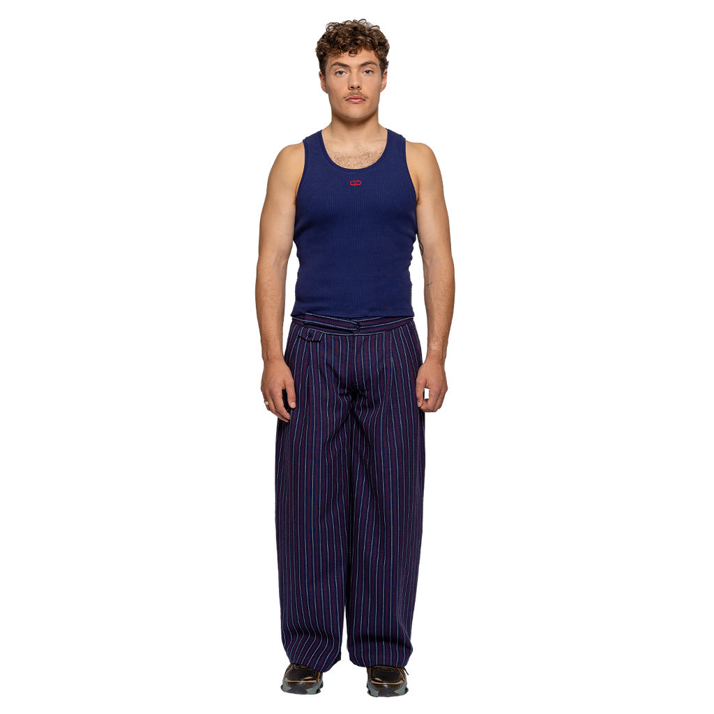 Man wearing a navy tank top and striped pants on a white background