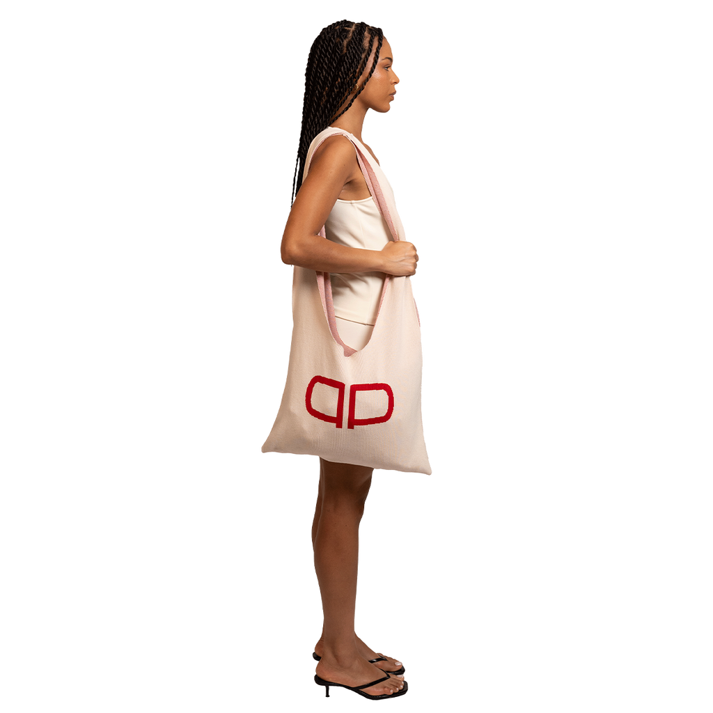 Woman holding a large tote bag with a visible brand logo on a white background