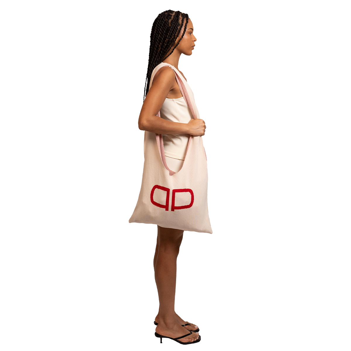 Woman holding a large tote bag with a visible brand logo on a white background