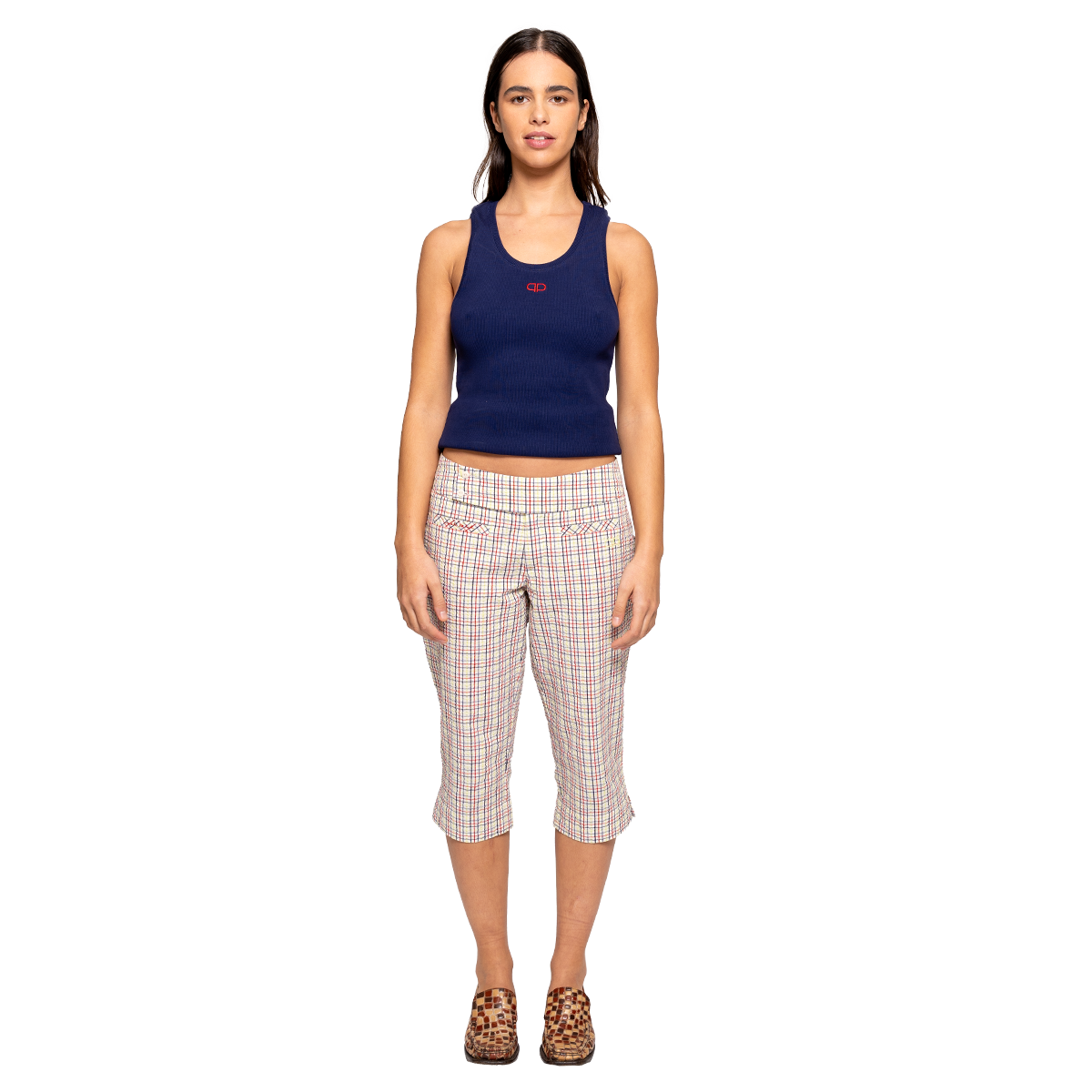 Woman wearing a navy tank top and plaid capri pants on a white background