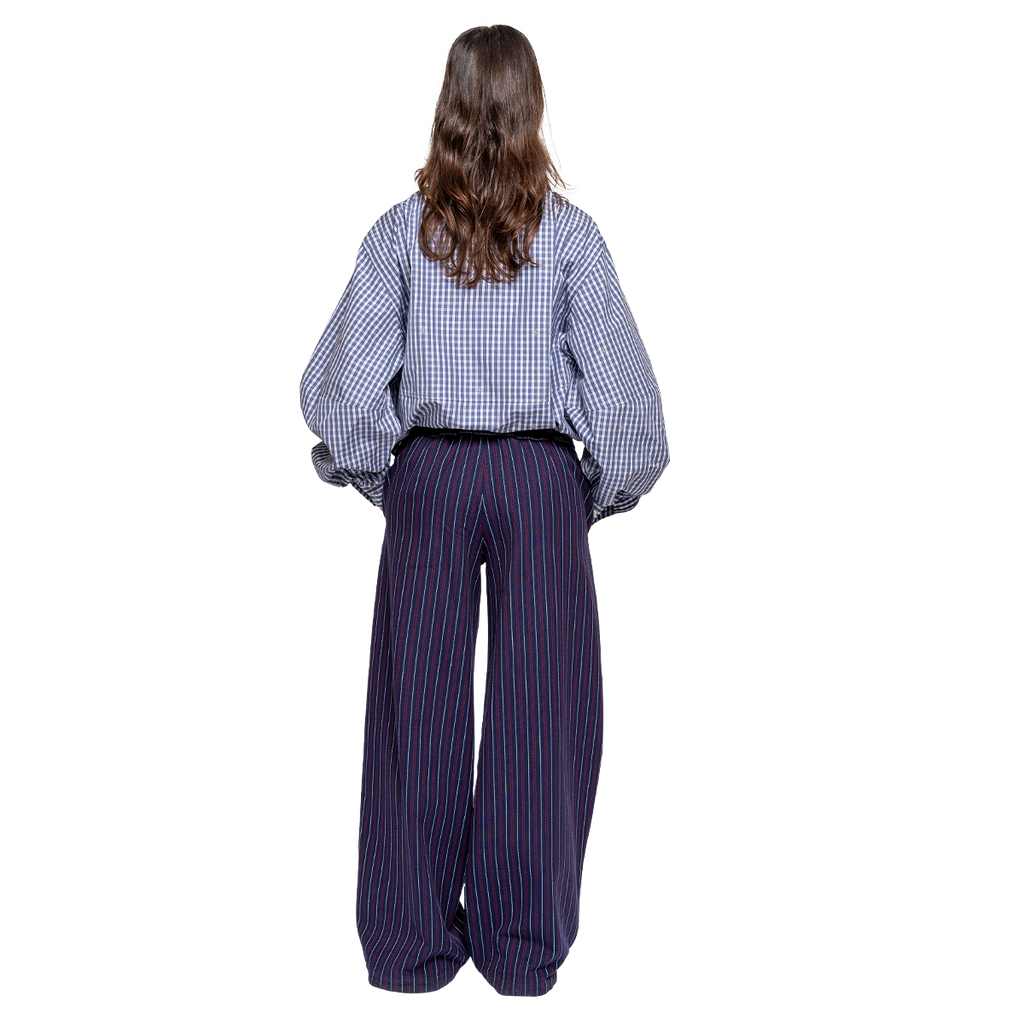 Person wearing a checkered shirt and striped pants on a white background