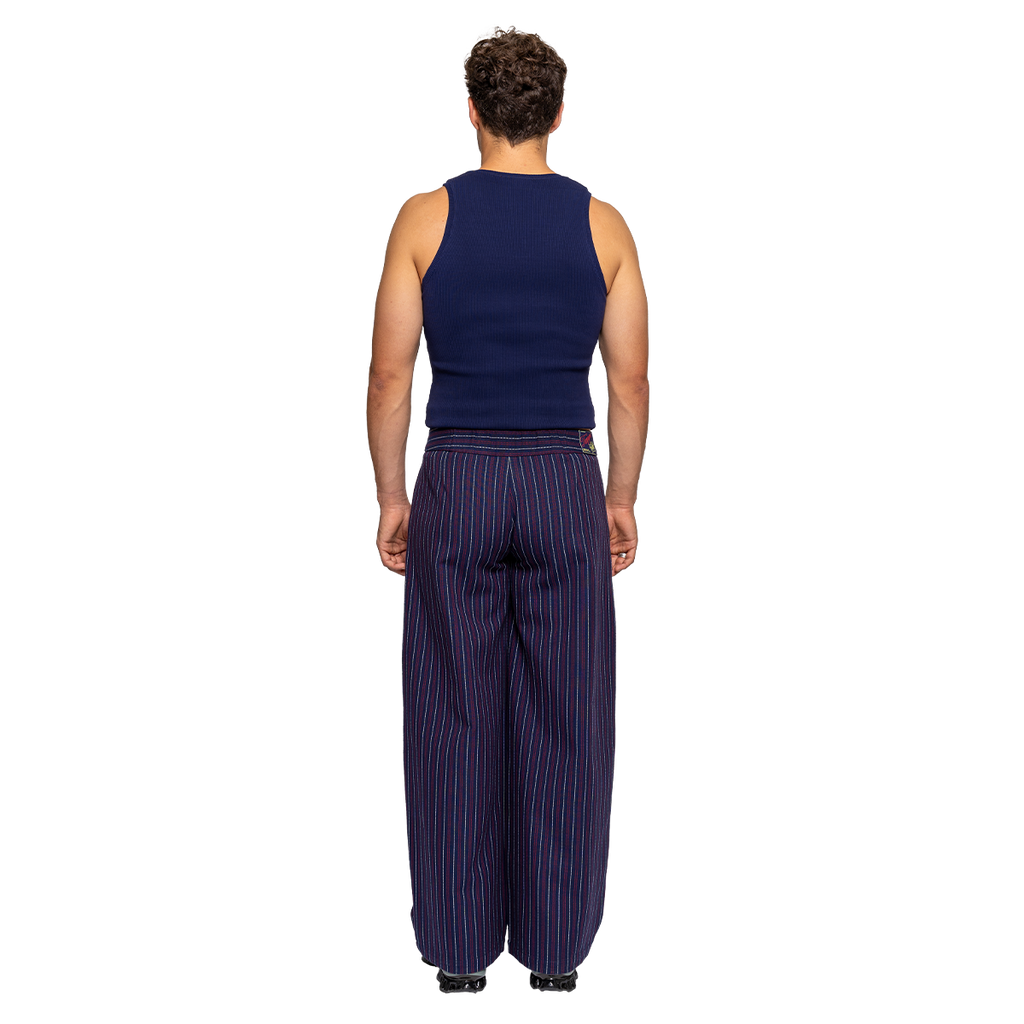 Person wearing a navy sleeveless top and wide-leg striped pants on a white background