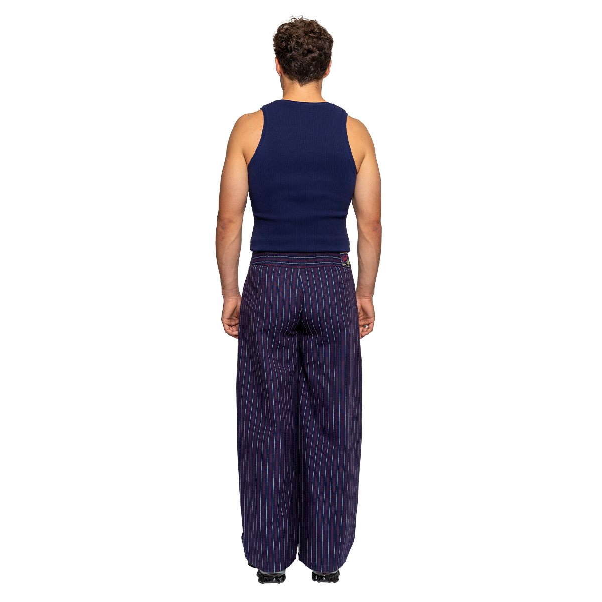 Person wearing a navy sleeveless top and wide-leg striped pants on a white background