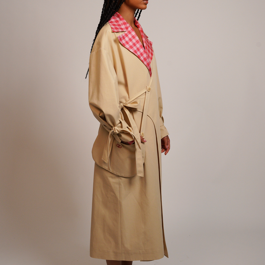 Person wearing a beige trench coat with a gingham collar