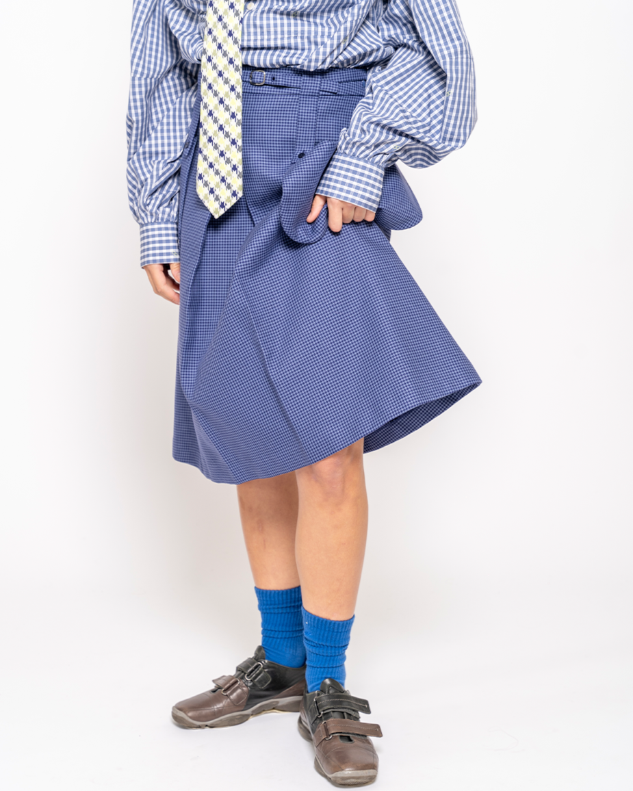 Person wearing a blue checkered shirt, tie, and skirt with blue socks on a white background