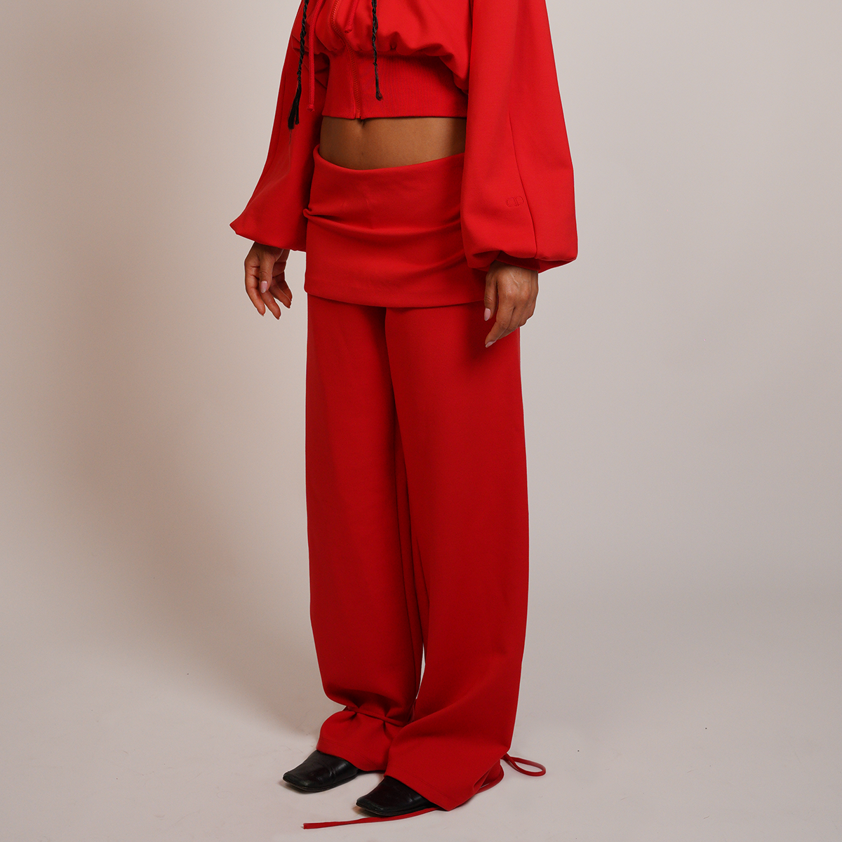 Person wearing a red outfit with wide-leg pants on a beige background