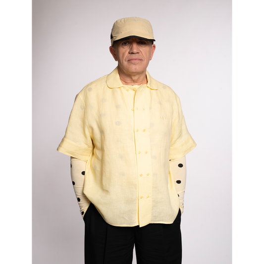 Yellow linen short-sleeve shirt with a mandarin collar, paired with black pants and a yellow cap.