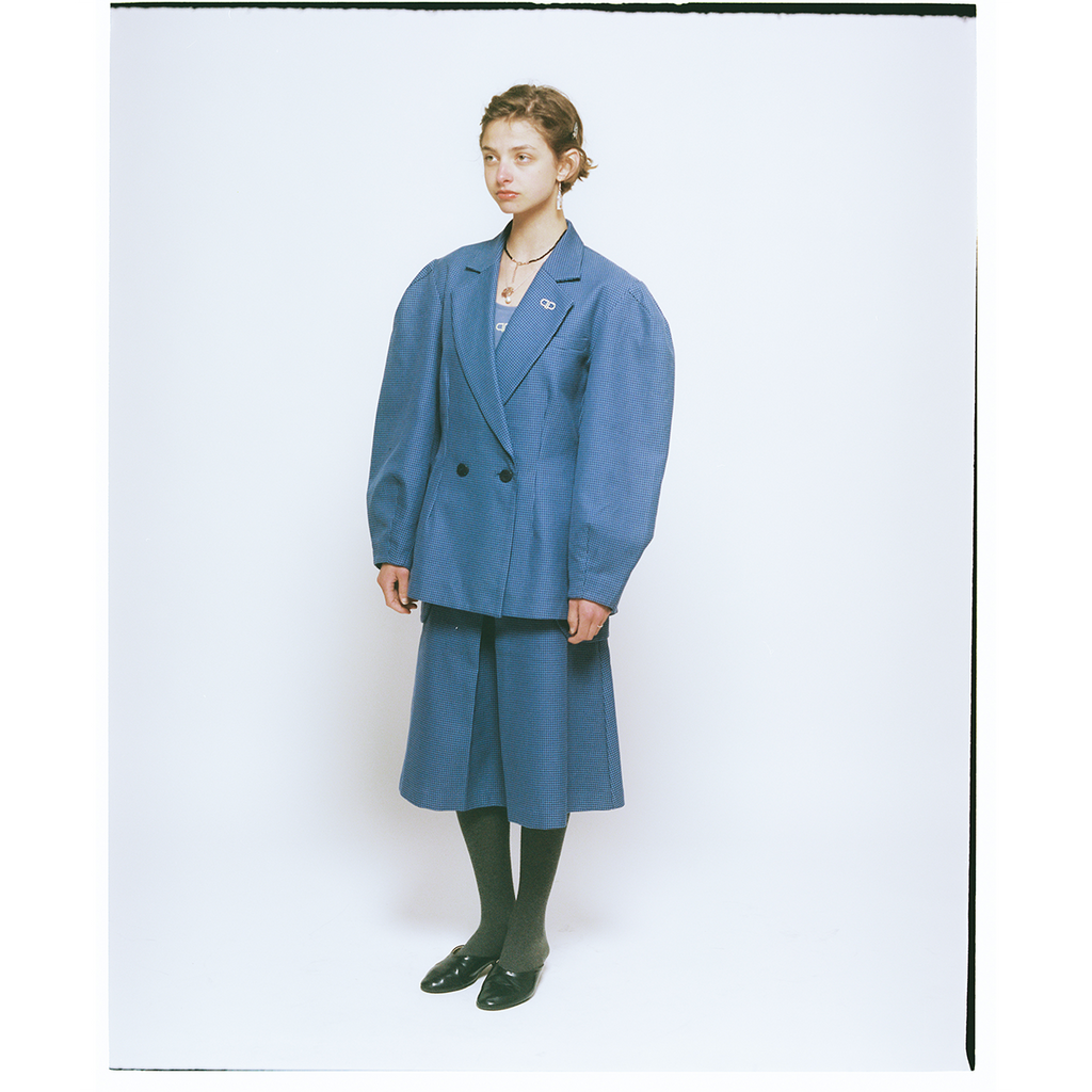 Person wearing a blue blazer and skirt set on a white background
