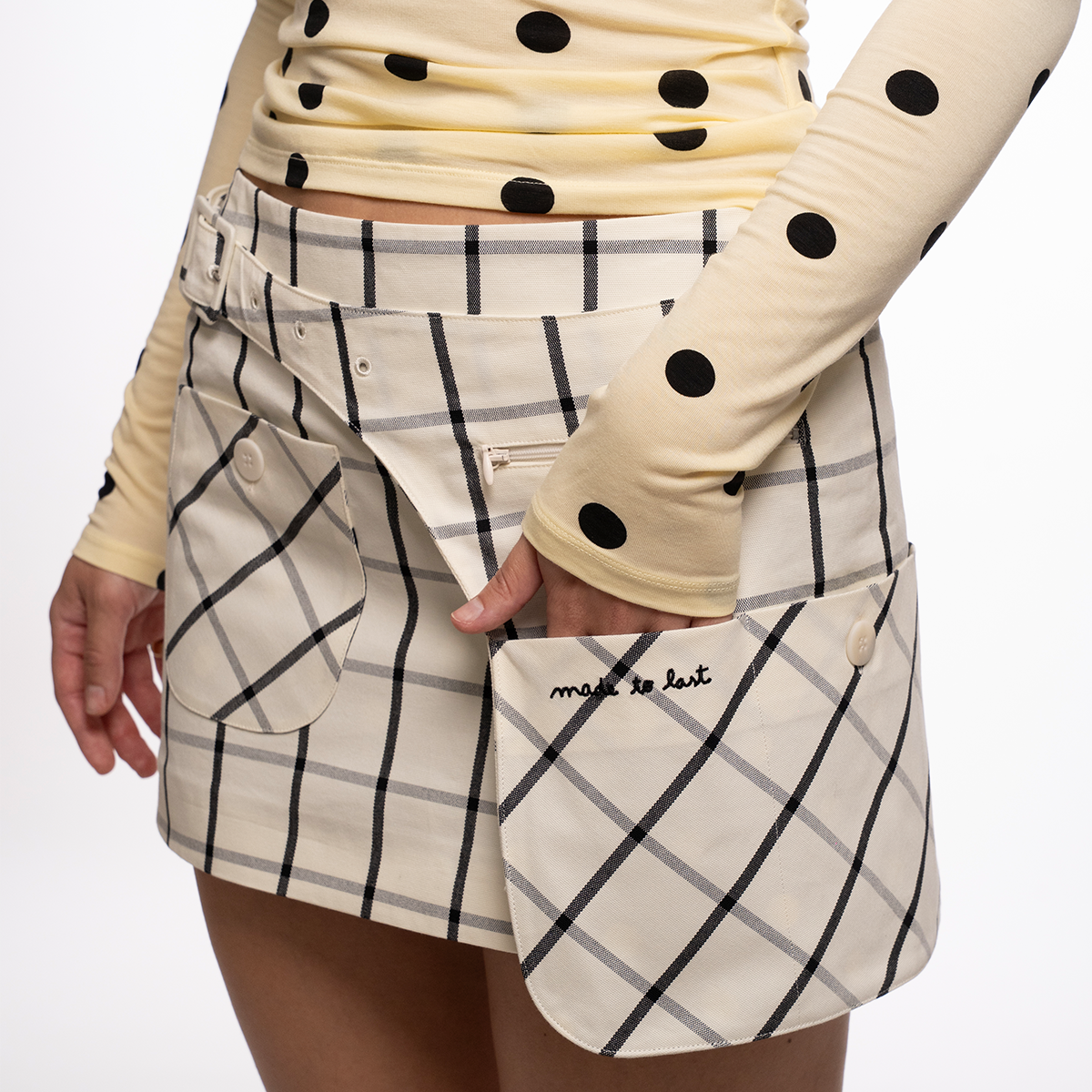 Person wearing a checkered skirt with a matching belt bag