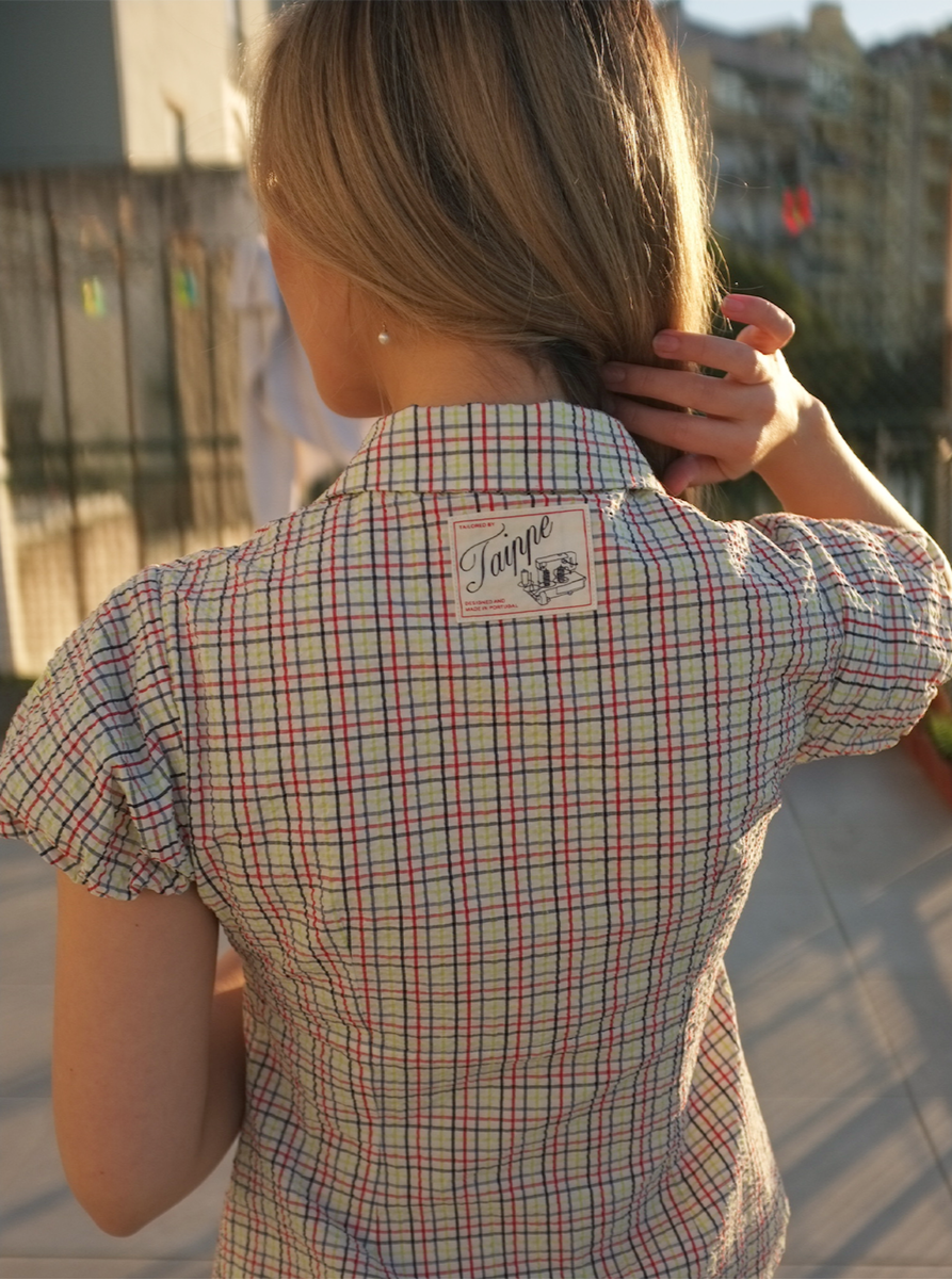 Person wearing a plaid blouse with a brand logo