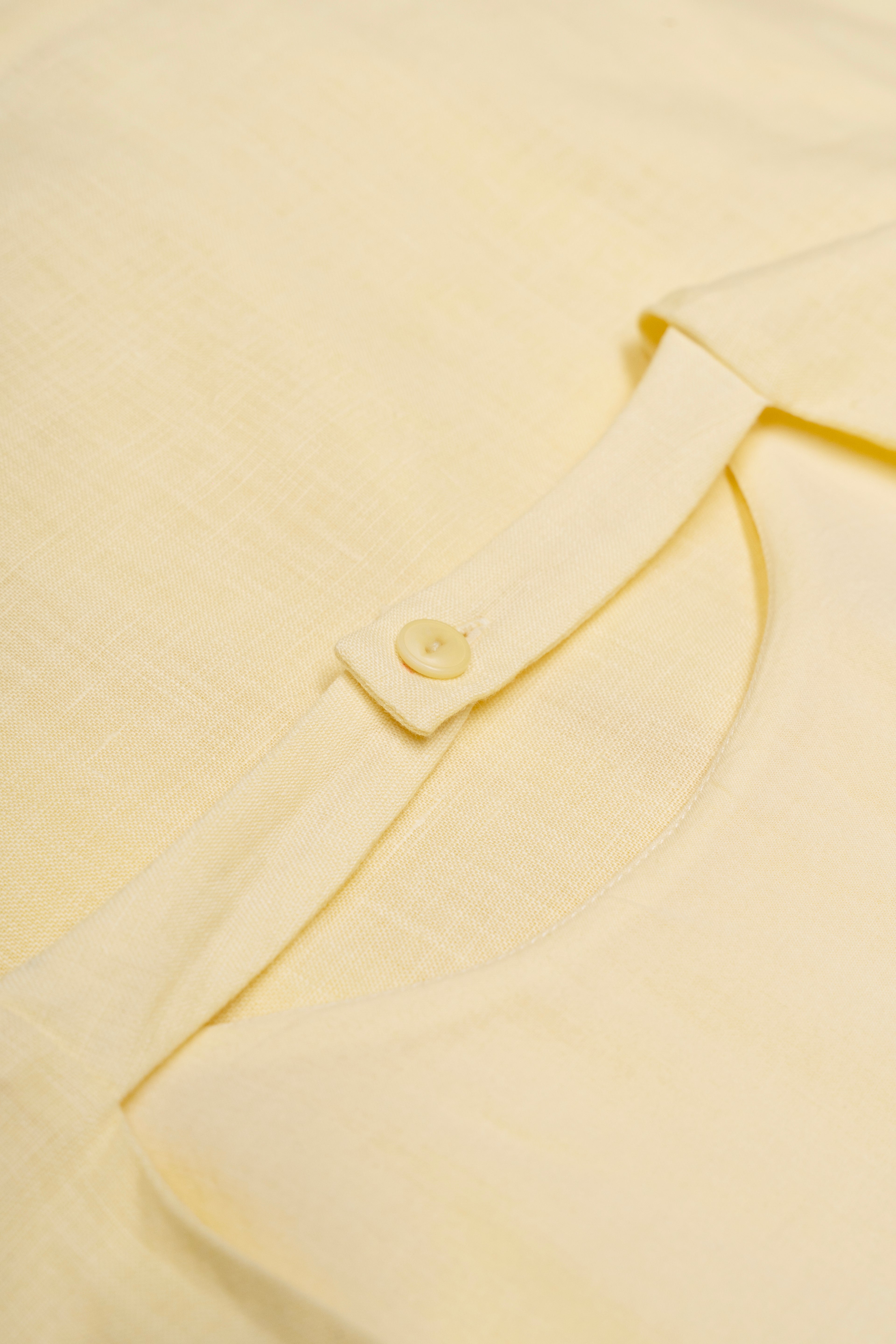 Close-up of a light yellow dress with a button detail