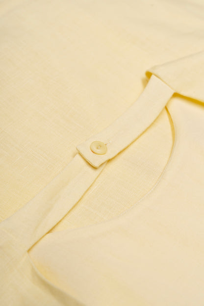Close-up of a light yellow dress with a button detail